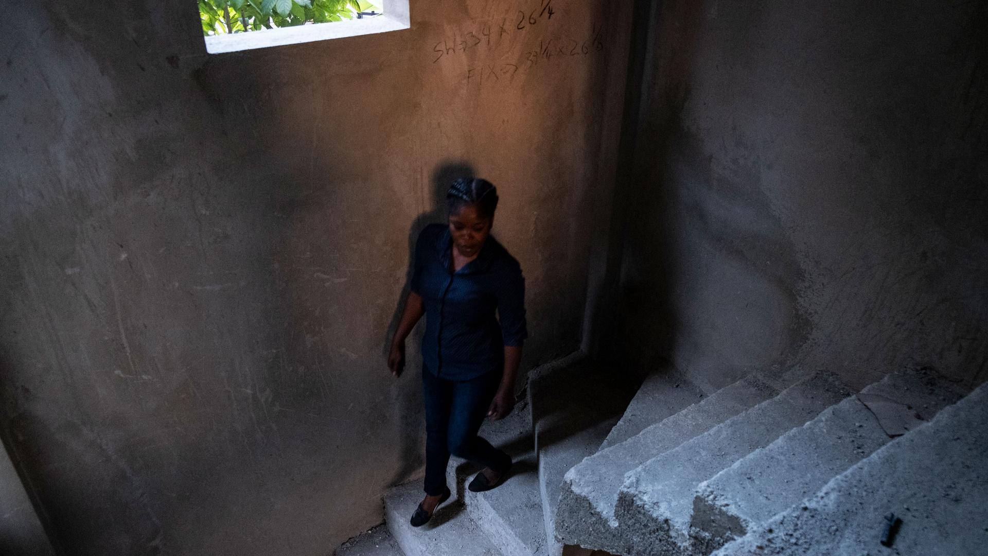 A woman is shown walking down a cement staircase in Port-au-Prince, Haiti.
