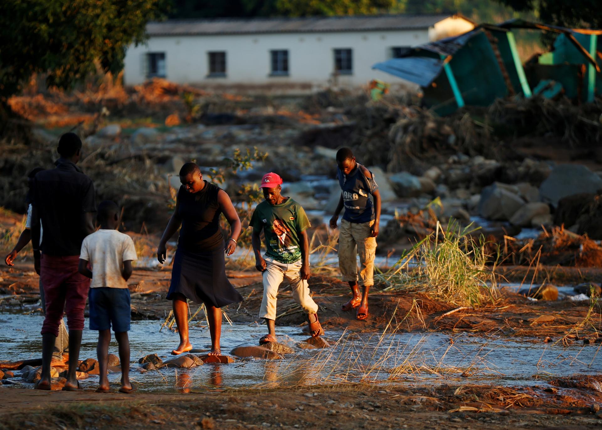 Survivors of Cyclone Idai walk through flooded waters to business center to receive aid.