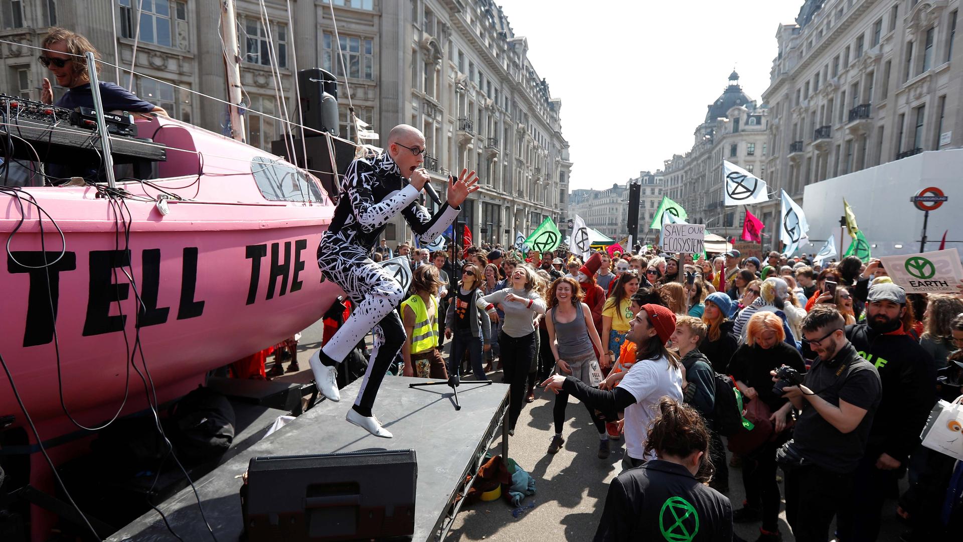 A man on a platform performs to a crowd of protestors