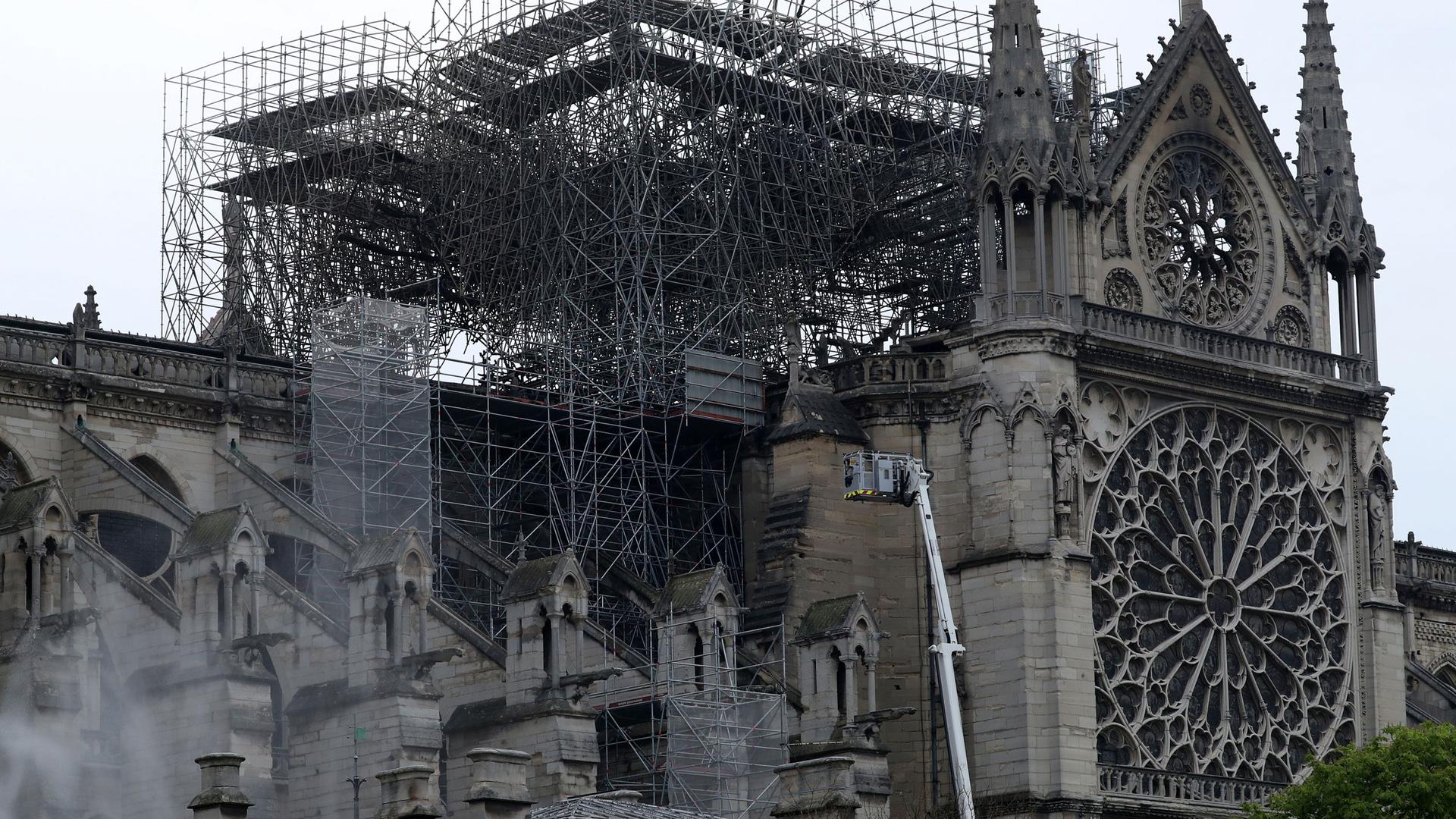 Smoke is seen rising around Notre-Dame Cathedral in Paris with some of the facade showing burn marks from the massive fire.