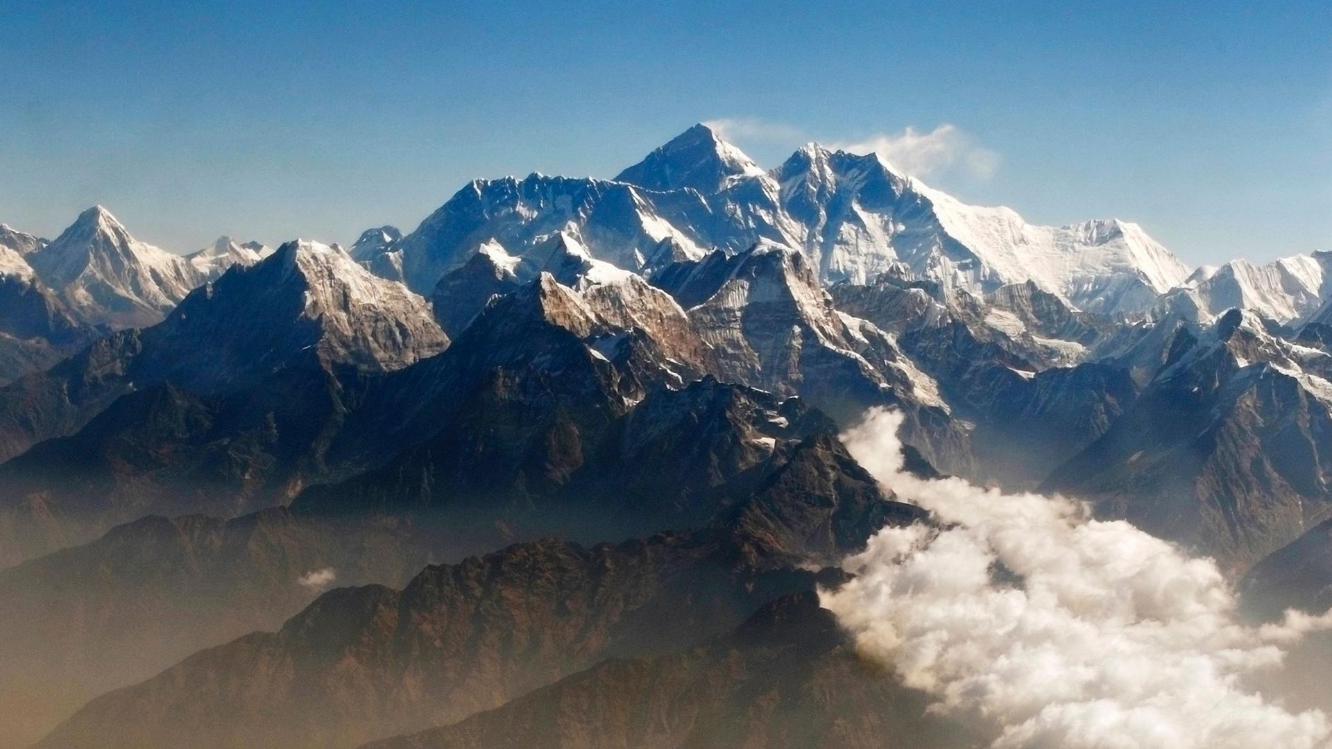Mount Everest and the Himalayan mountain range covered in snow, seen from above. 