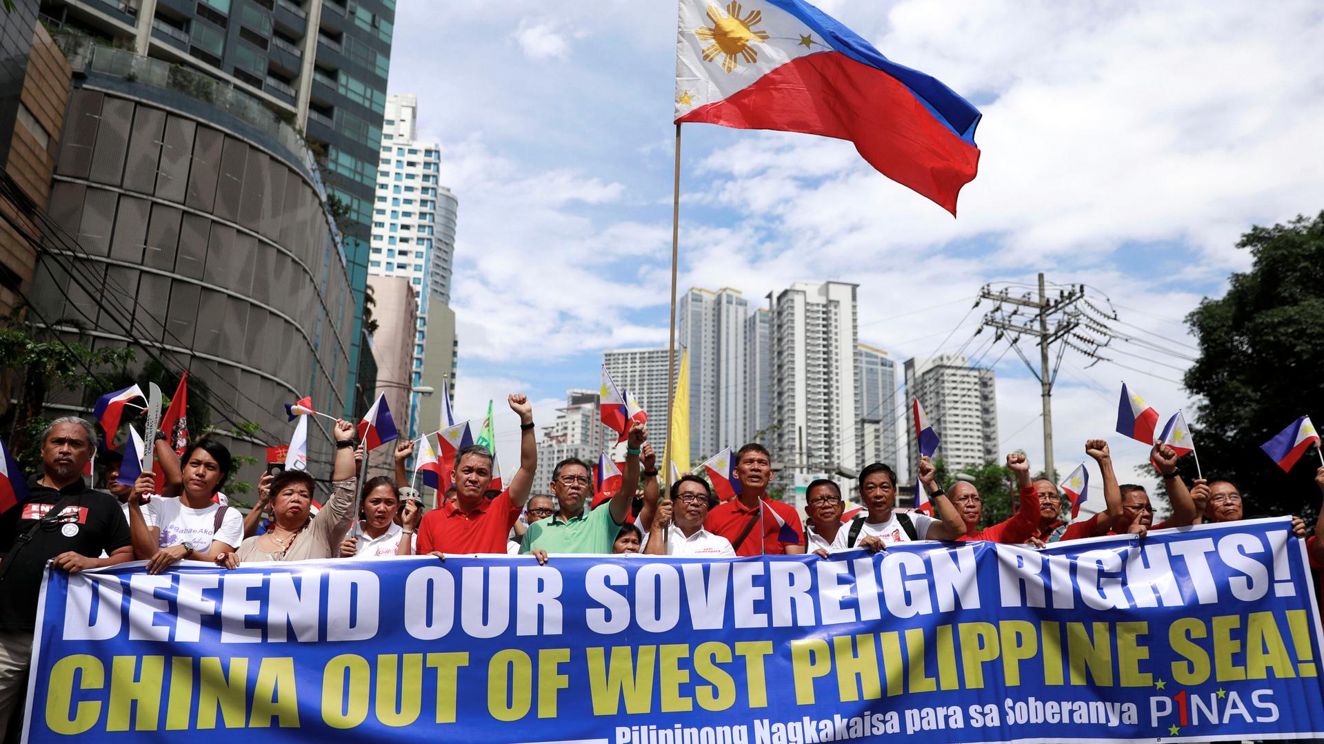 protesters carry blue and red signs saying 'defend our sovereignty'