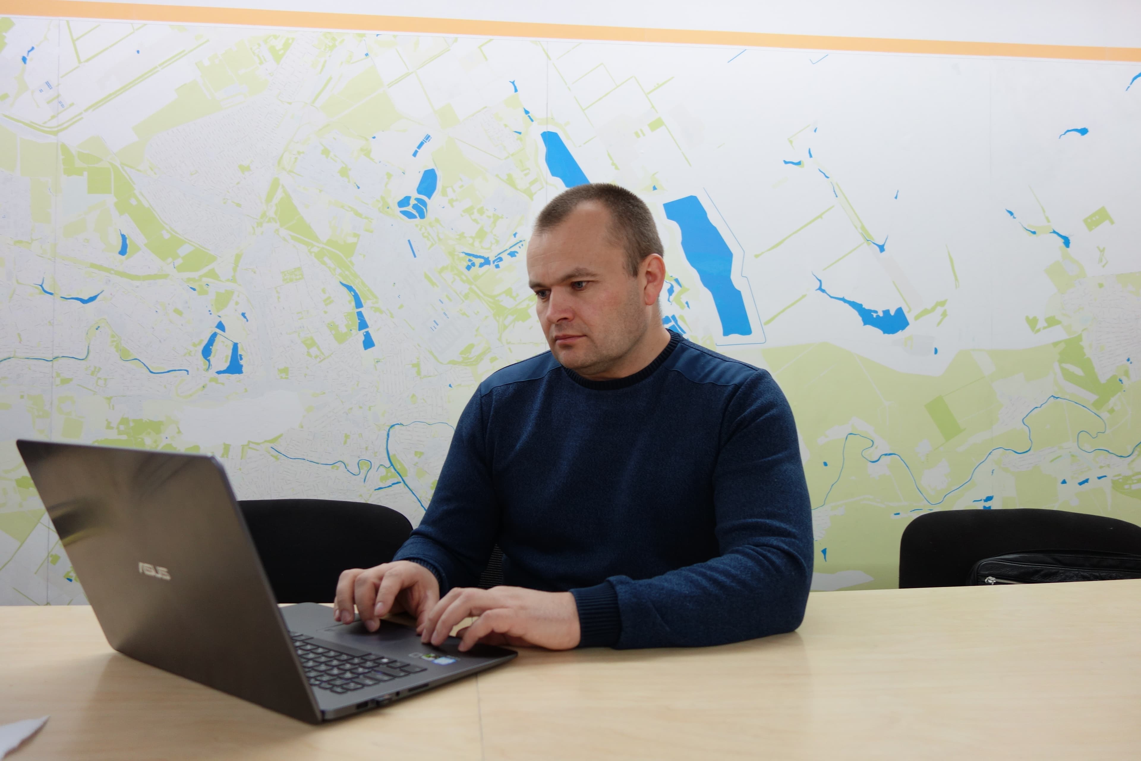 Man sits at his desk typing on laptop.