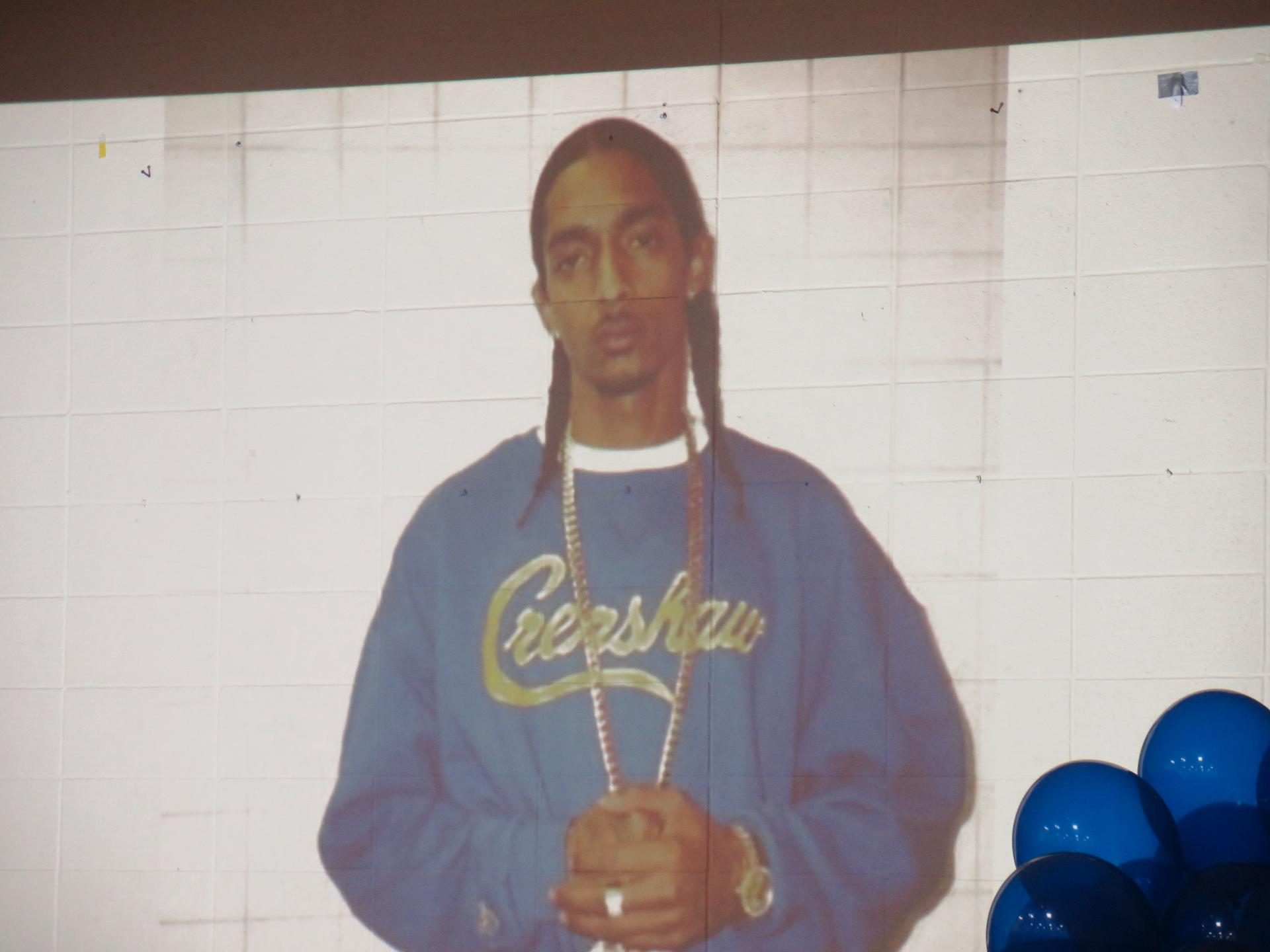 A photo of a black man with a shirt that says Crenshaw is projected on a wall
