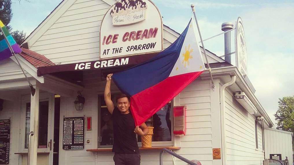 Rayben Tamayo stands in front of the ice cream counter for his summer employer, the Hot Chocolate Sparrow on Cape Cod, Massachusetts. The owners put up a Philippine flag to honor their many seasonal summer employees.