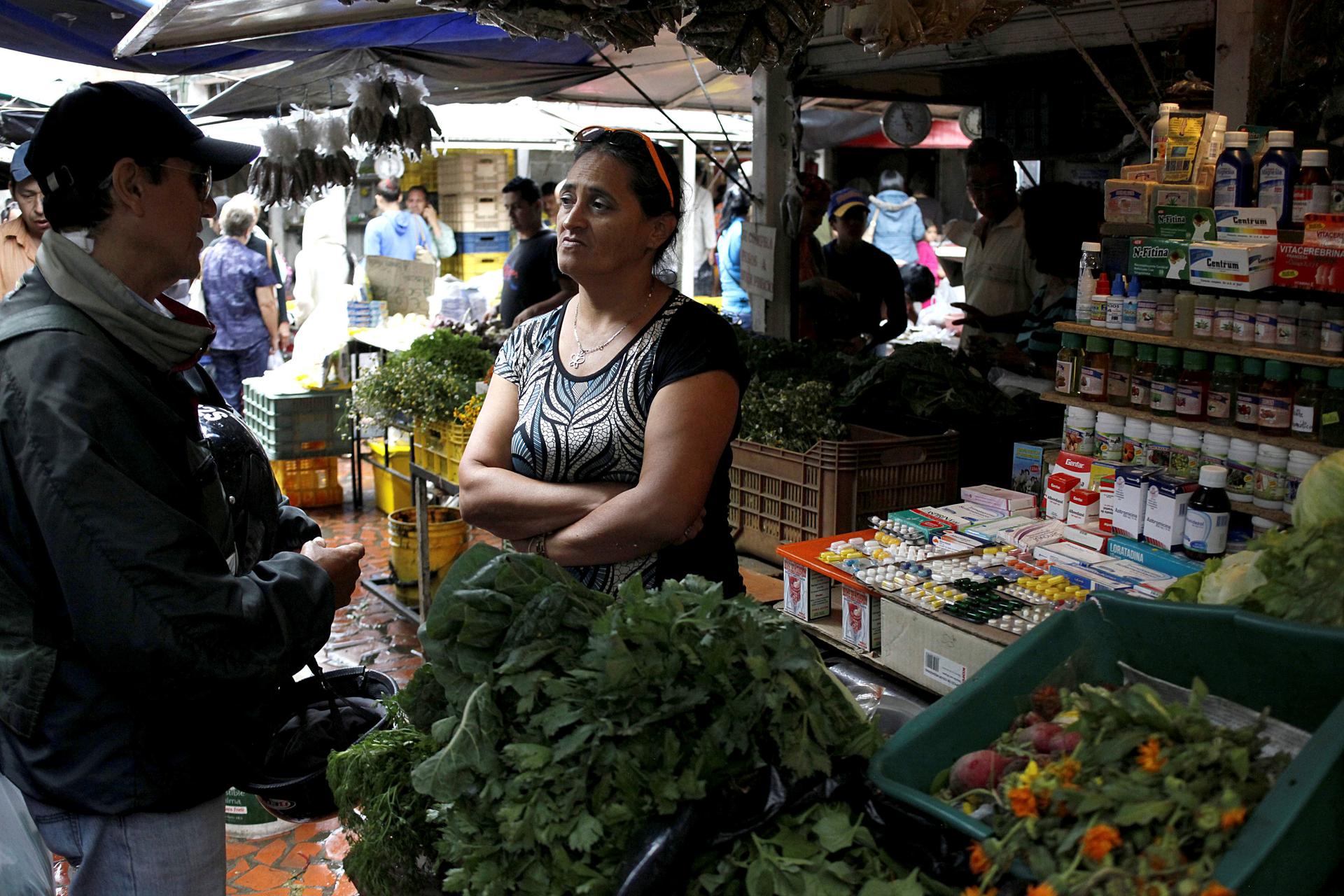 A vendor talks with a customer in her fruit and vegetables stall selling medicines at a market in Rubio, Venezuela.