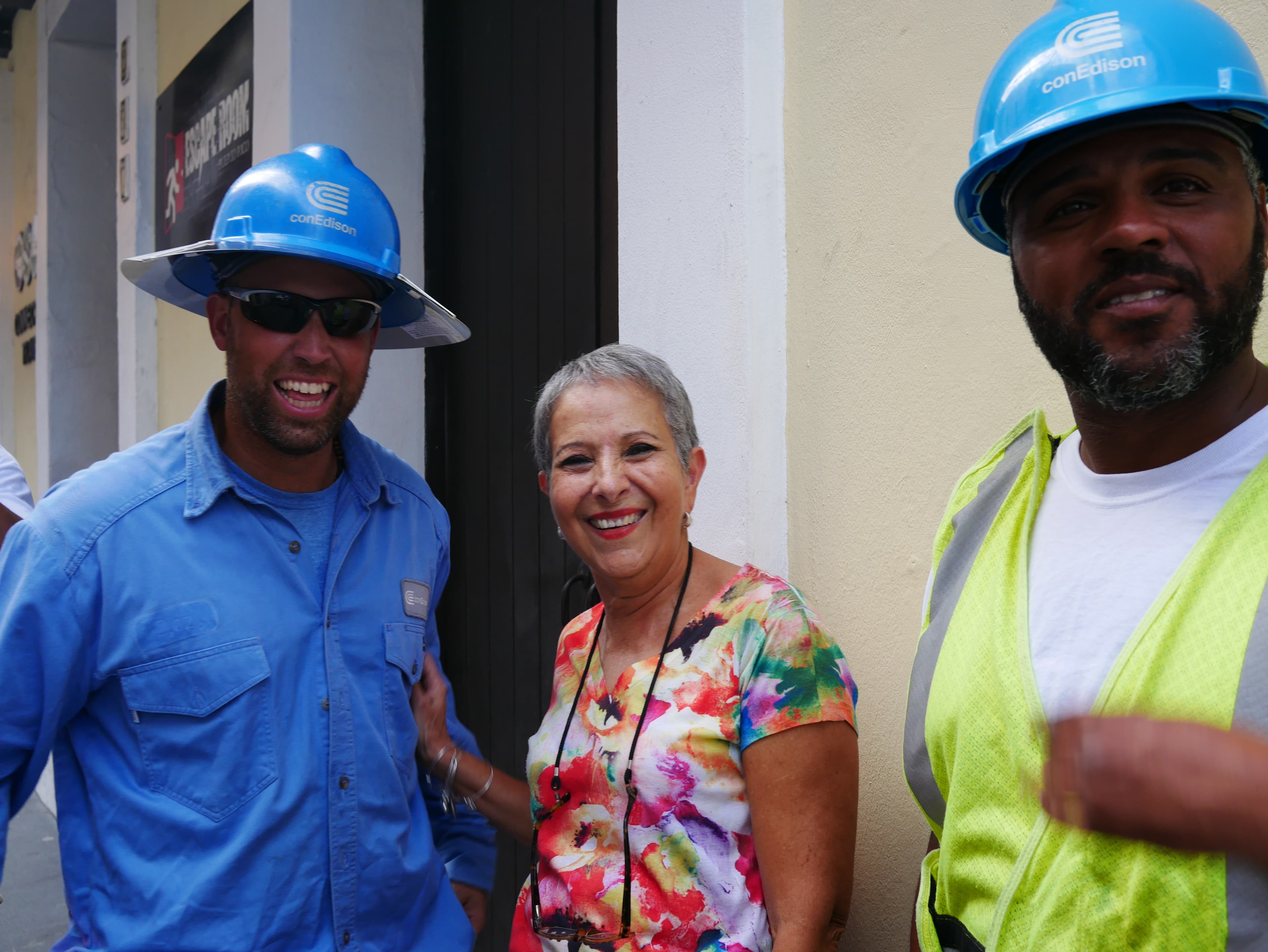 Marisol Maldonado poses with Con Ed linemen minutes after they restored electricity to the travel agency where she works in Old San Juan.