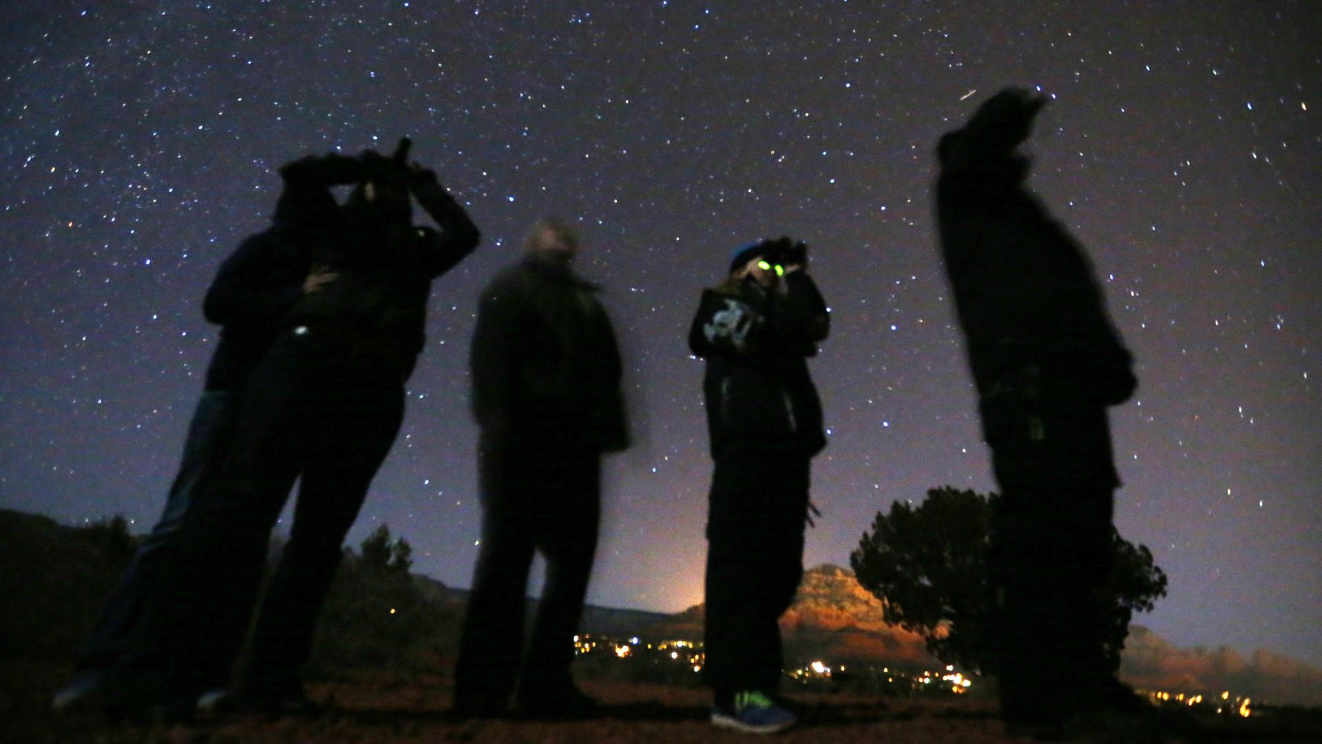 People use night vision goggles to look at the night sky during an Unidentified Flying Object (UFO) tour in the desert outside Sedona, Arizona, Feb. 14, 2013.