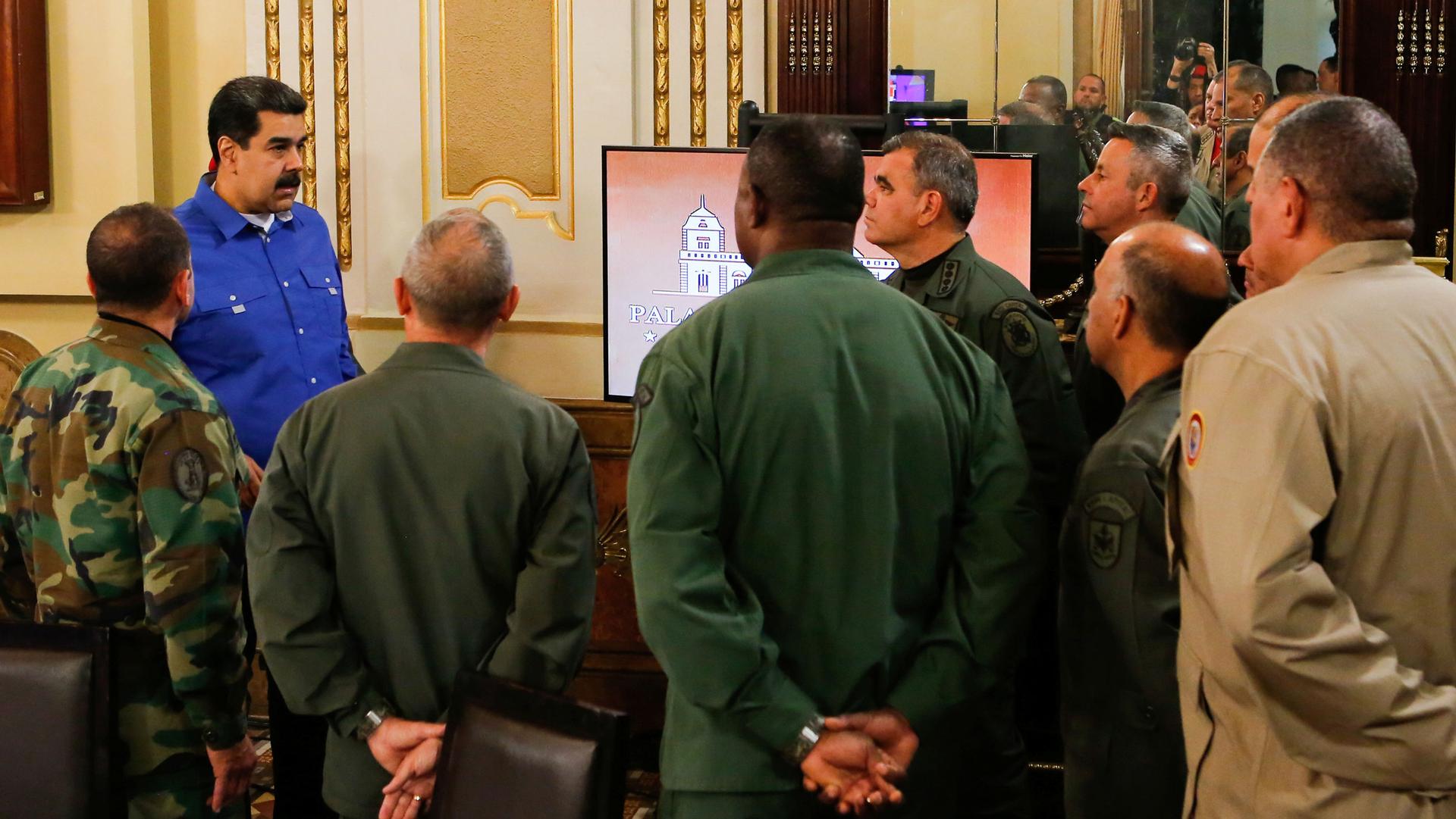 Venezuela's President Nicolás Maduro is shown wearing a blue shirt standing among a group of military authorities.