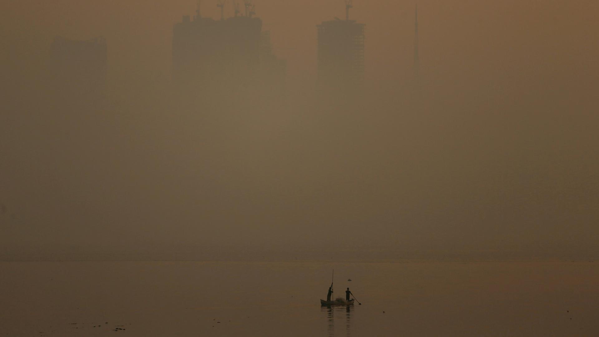 a fishing boat in front of a very smoggy mumbai