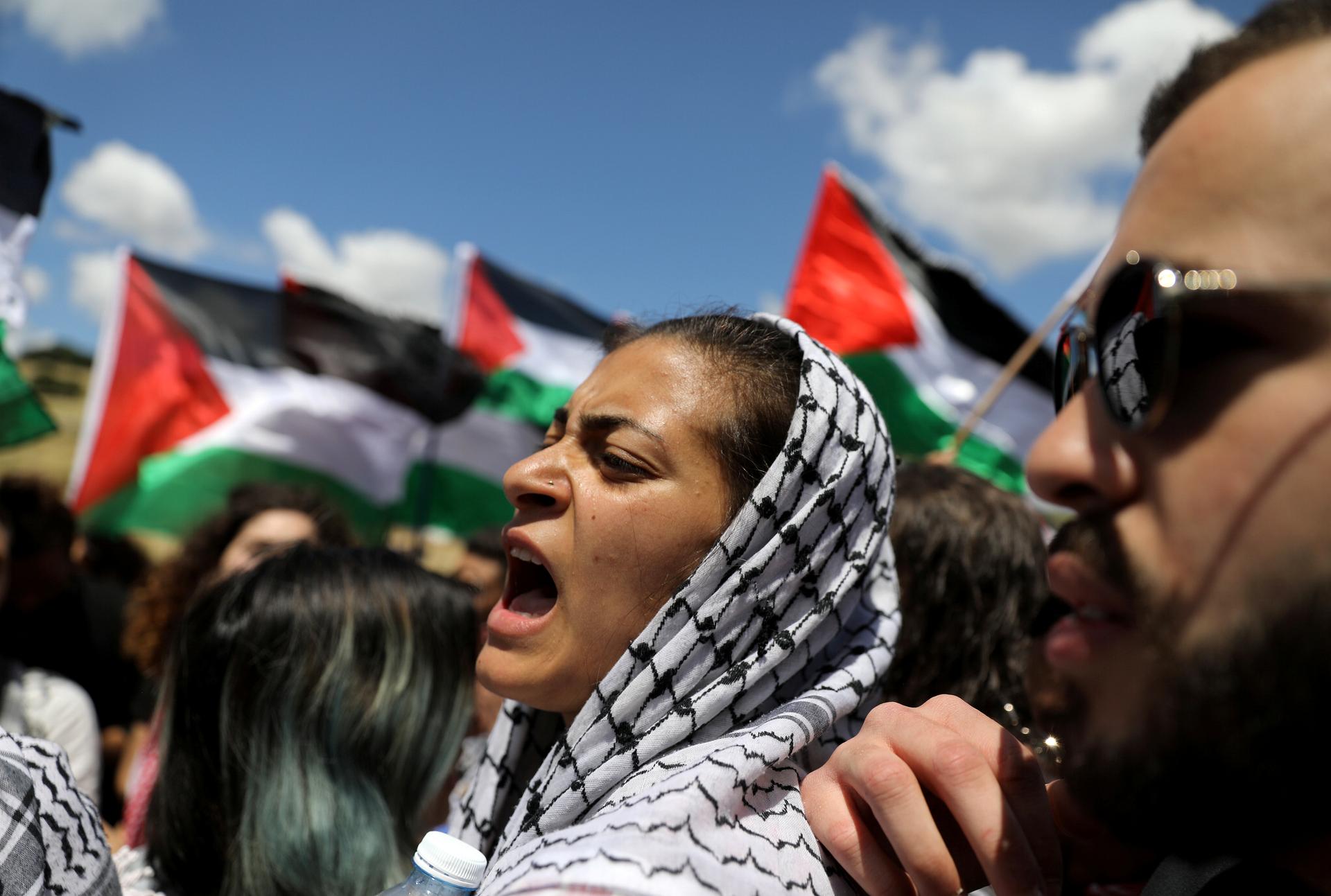A woman shouts next to protesters holding Palestinian flag.