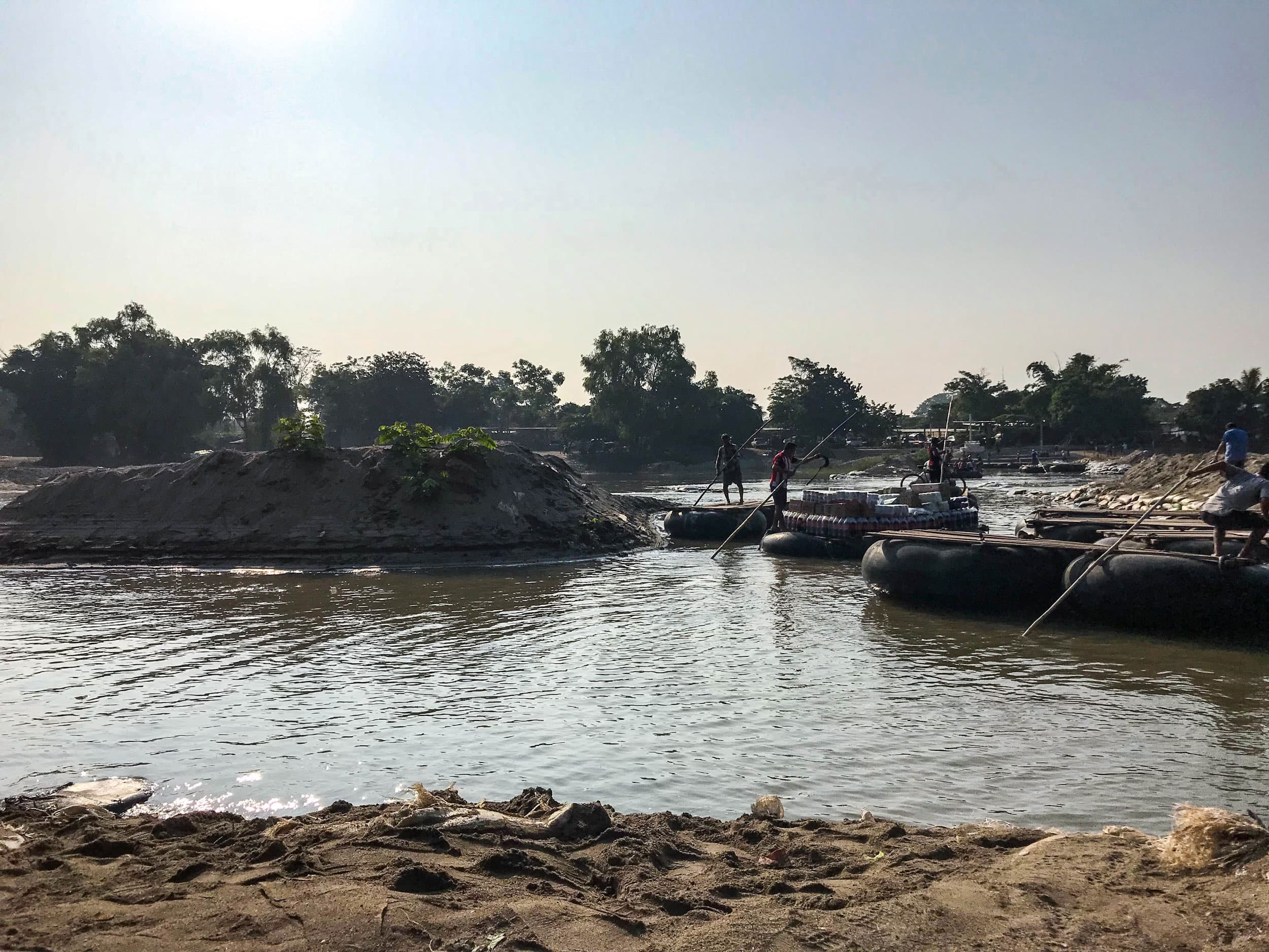 Men are shown on top of rafts with wooden tops on a river.