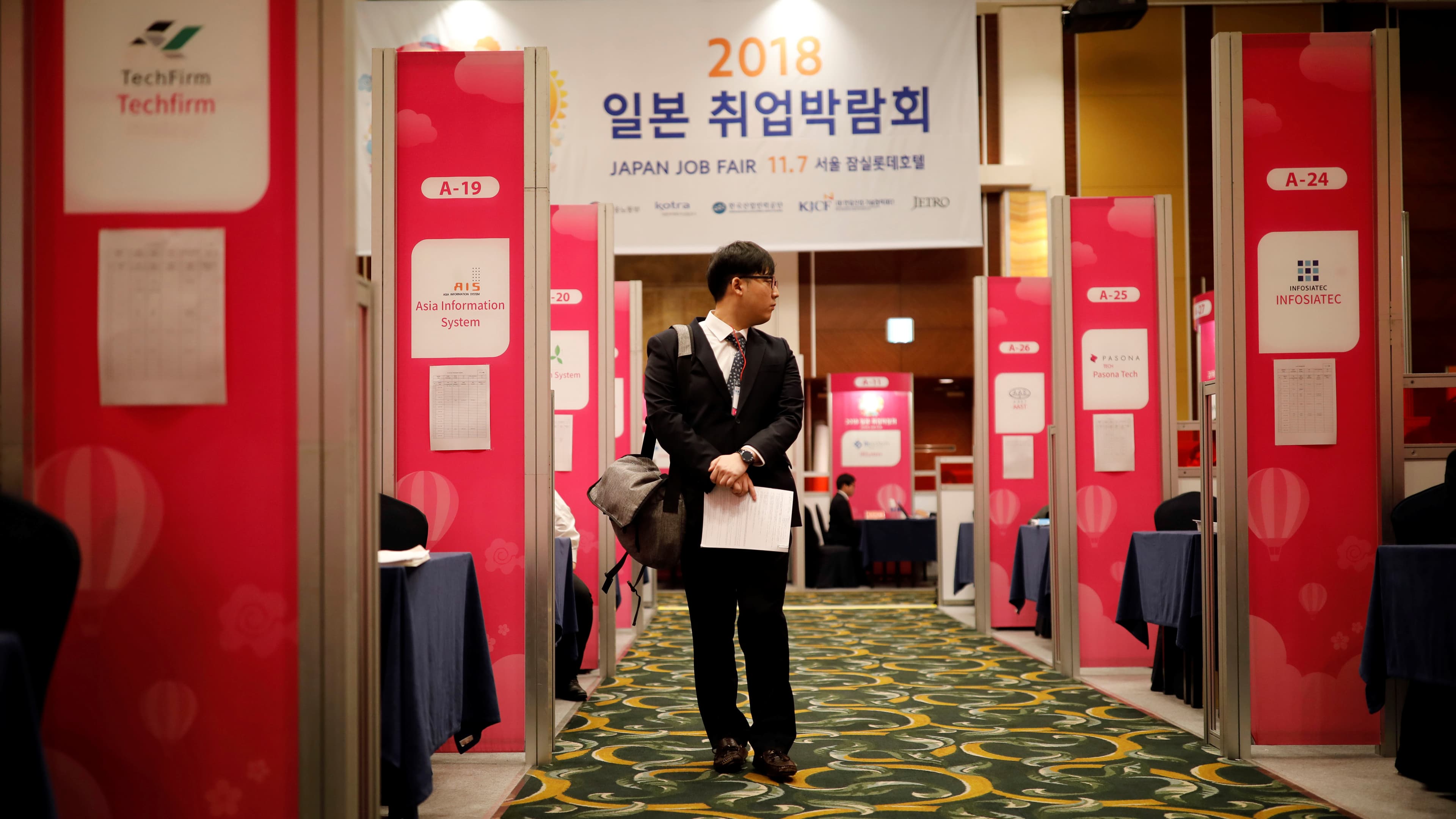 A man walks along corridor between booths
