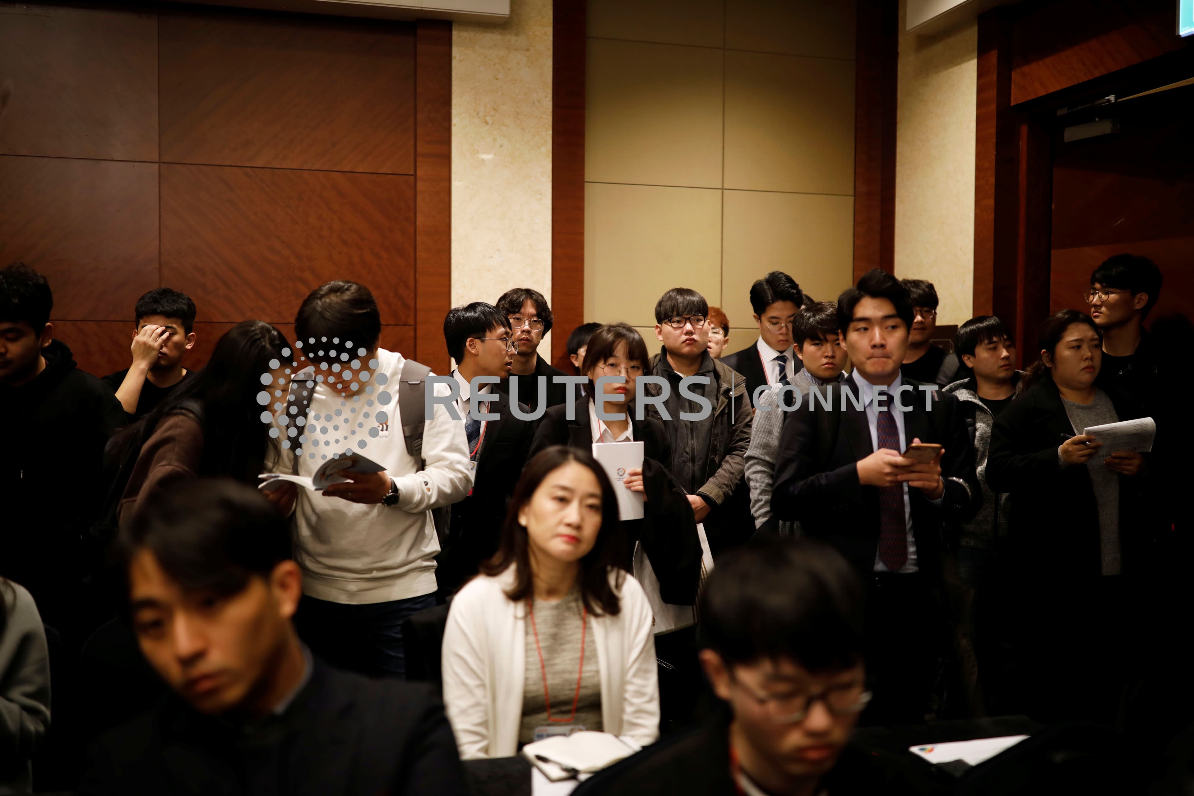 A group of forlorn-looking young people in business attire