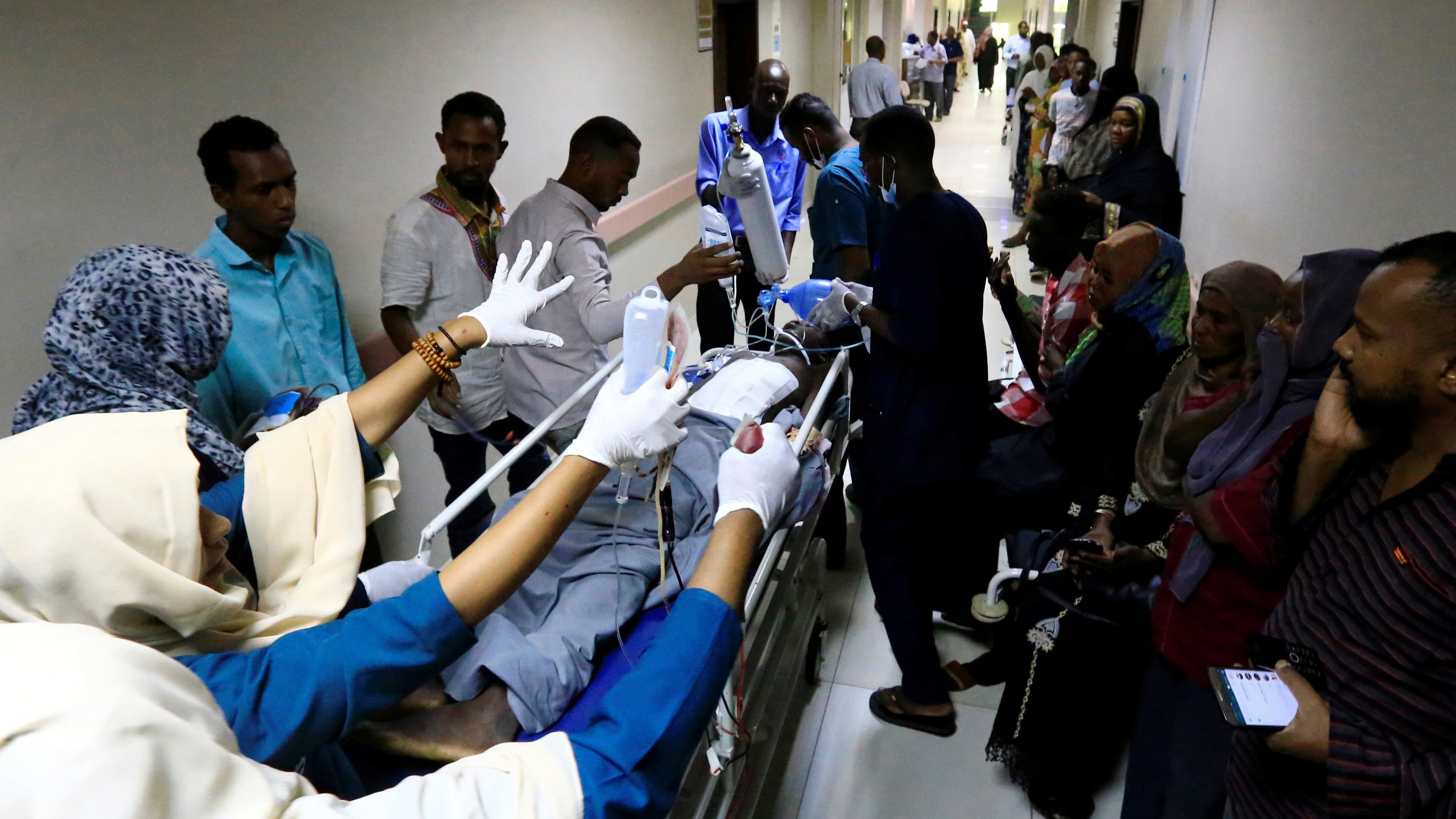 A gurney is rushed down a crowded hallway in a hospital