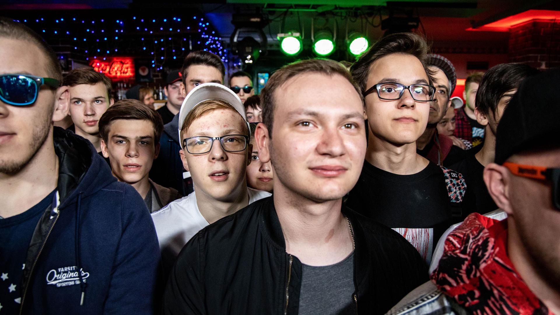 Several young men are shown looking past the camera with some wearing glasses.