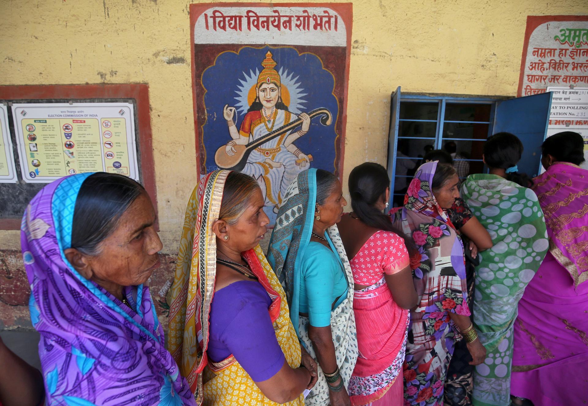 Women in colorful saris line up to vote