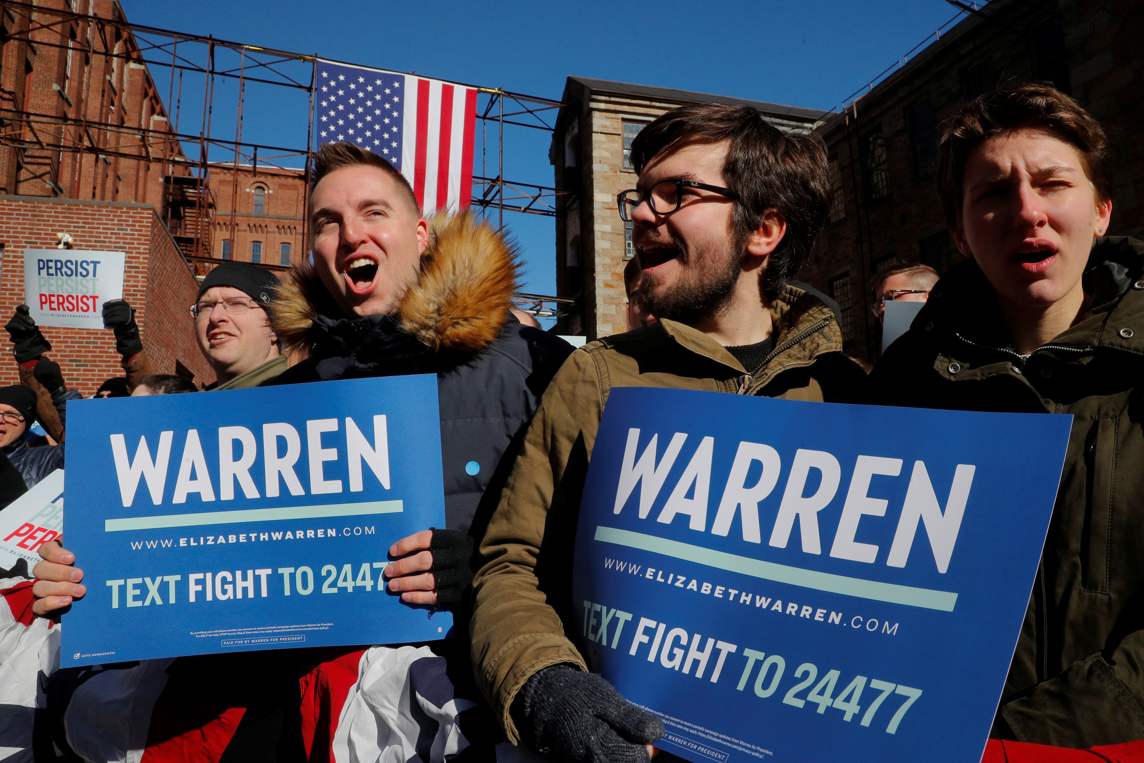 Young men hold campaign signs for Elizabeth Warren.