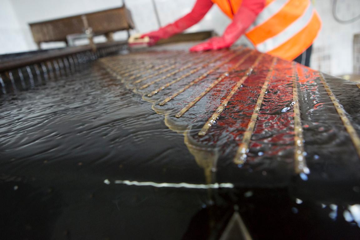 A slurry of water and silt trickles across a shaking table inside the Bornuur plant. The table uses water and gravity instead of water and mercury to separate out gold particles.