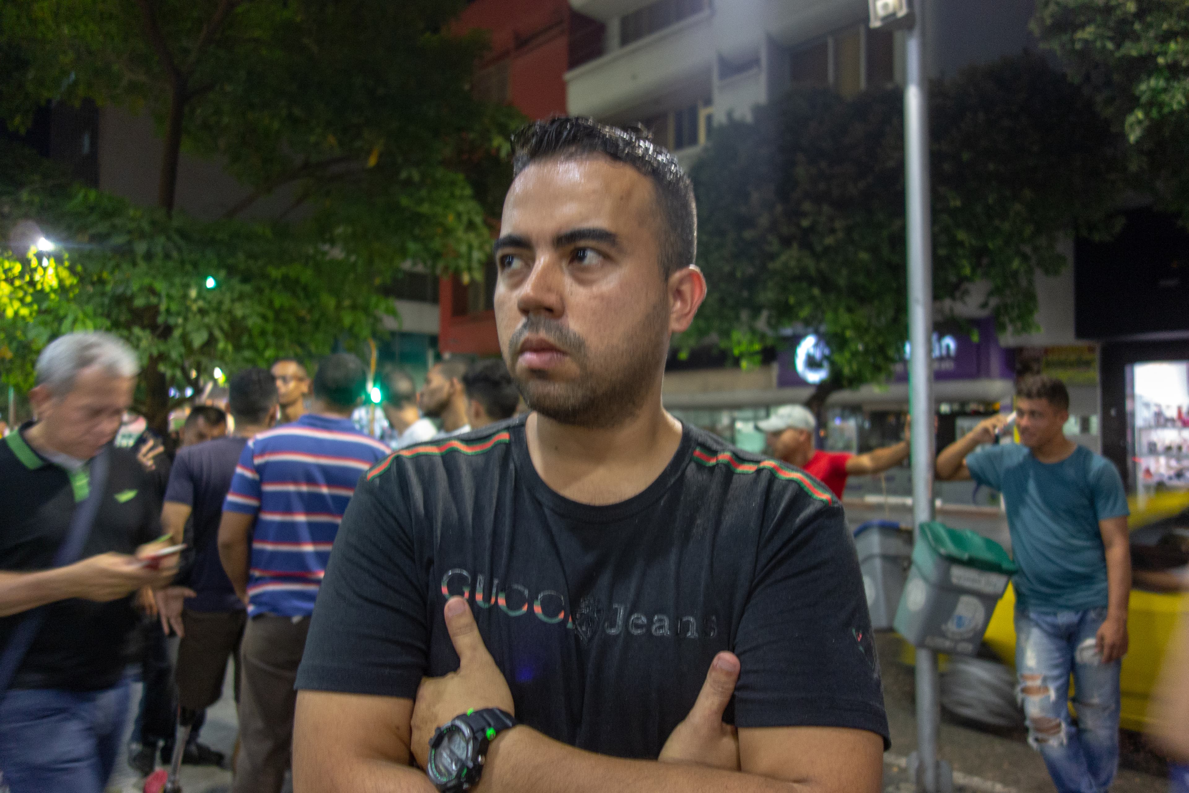 A man folds his arms over his chest wearing a black shirt