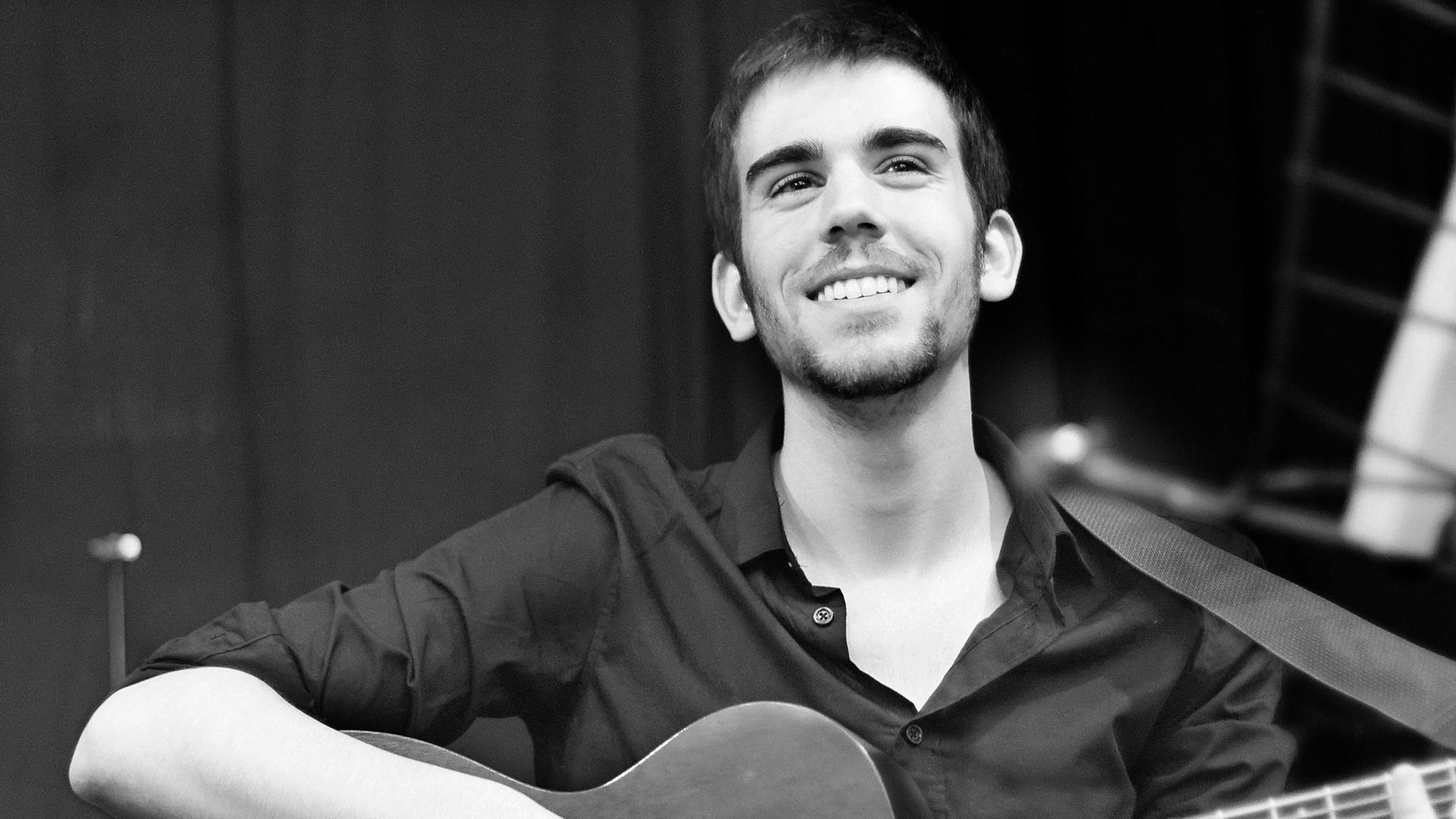 Baptiste Chevreau holding his guitar, smiling
