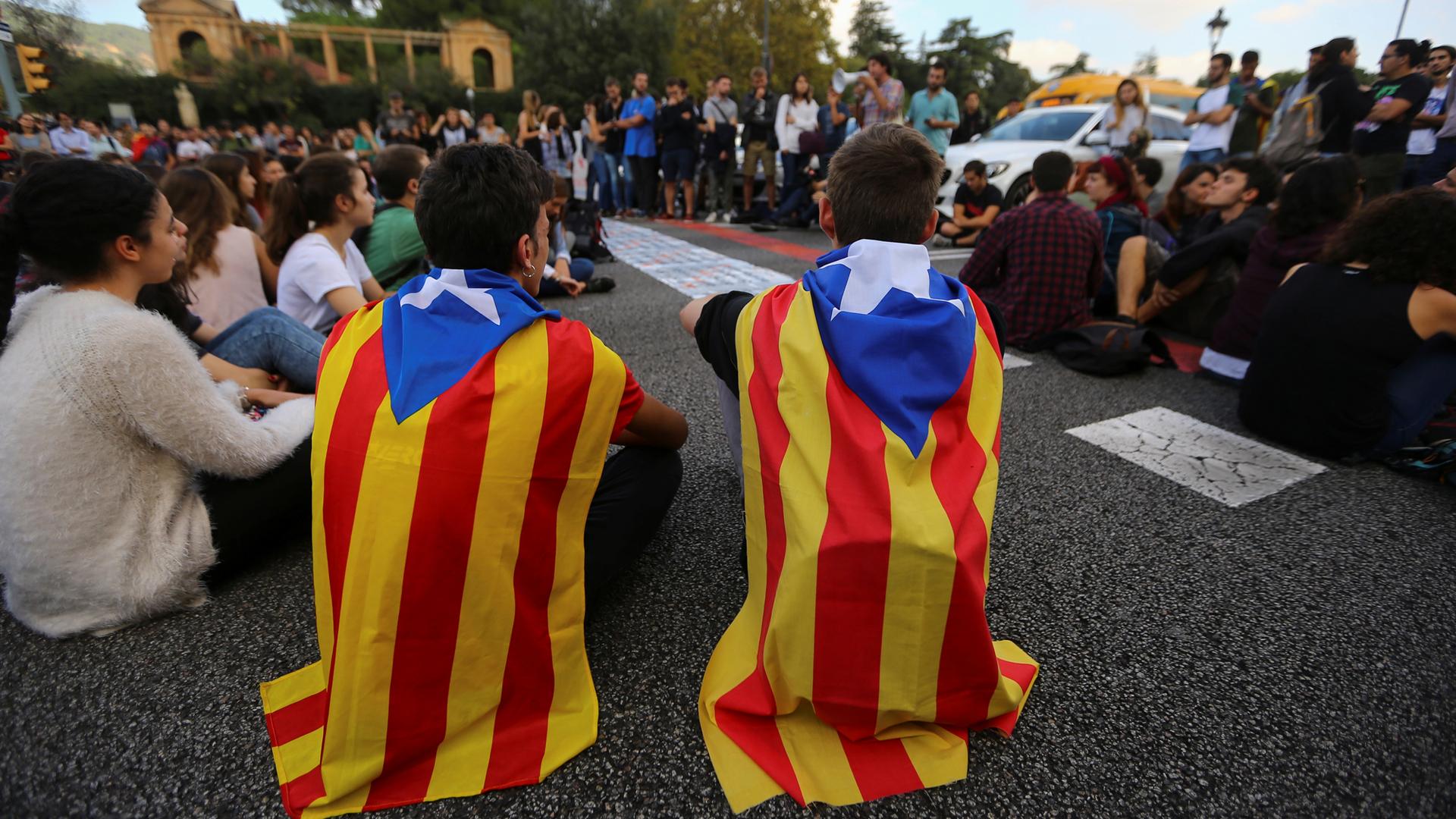 Students wear Catalan flags as they block a street during a protest in Barcelona.