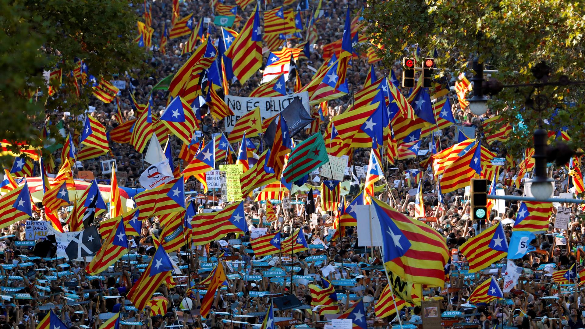 People wave Catalan flags during a demonstration organized by Catalan pro-independence movements following the imprisonment Jordi Sanchez and Jordi Cuixart, in Barcelona, Oct. 21, 2017.