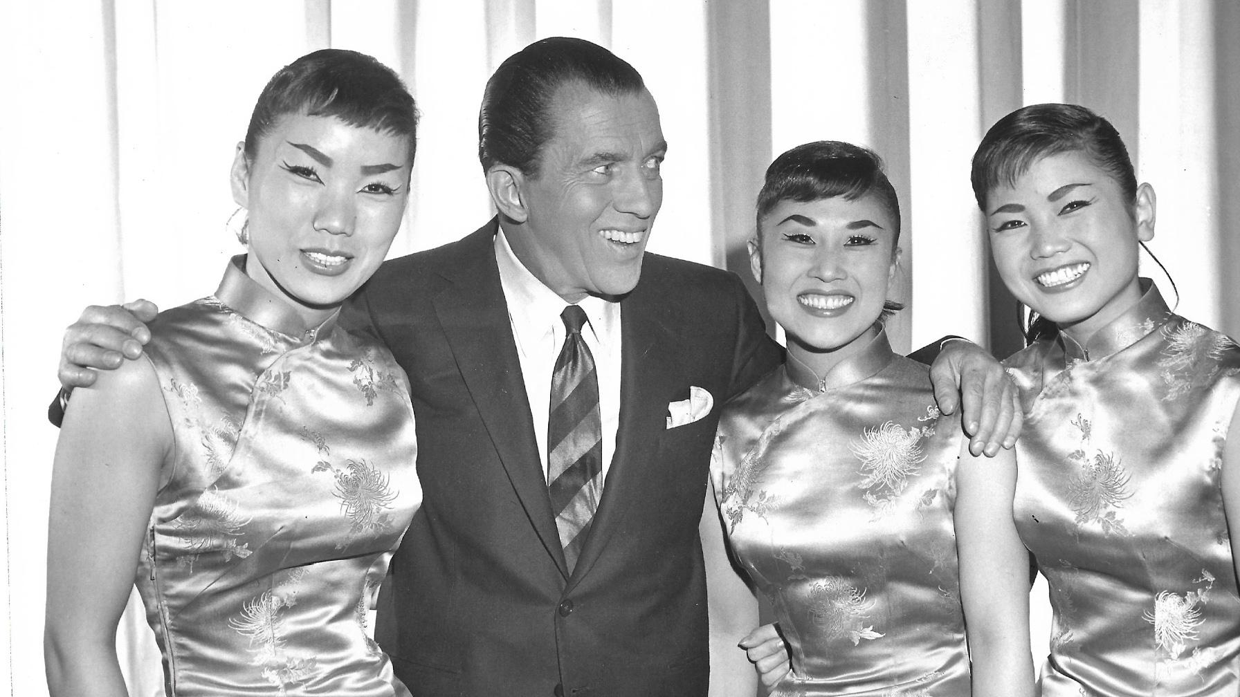 black and white photo of three women and a man standing on stage