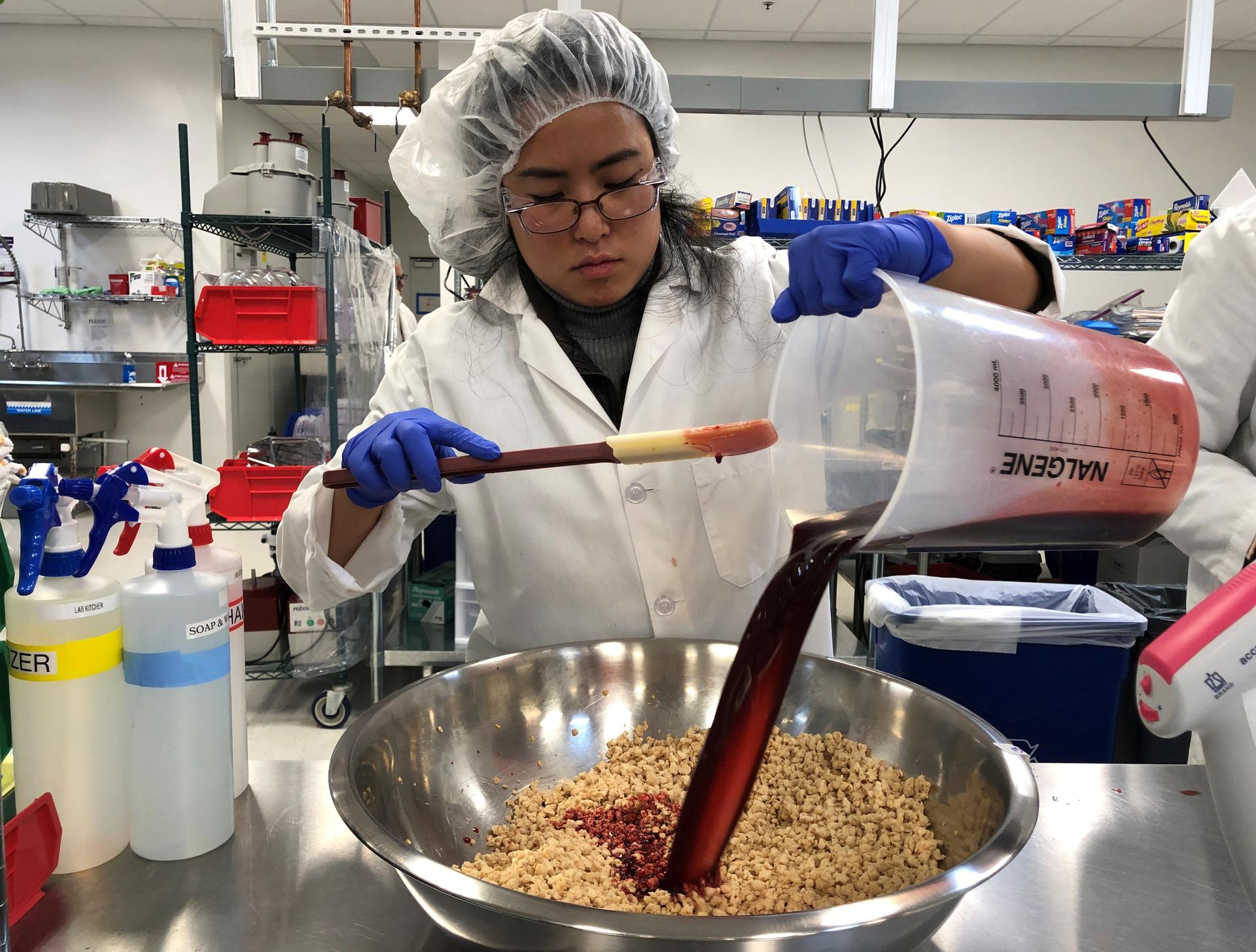 Impossible Foods research technician Alexia Yue pours a heme solution, the key ingredient, into a plant-based mixture for burgers at the company's facility in Redwood City, California. March 26, 2019.