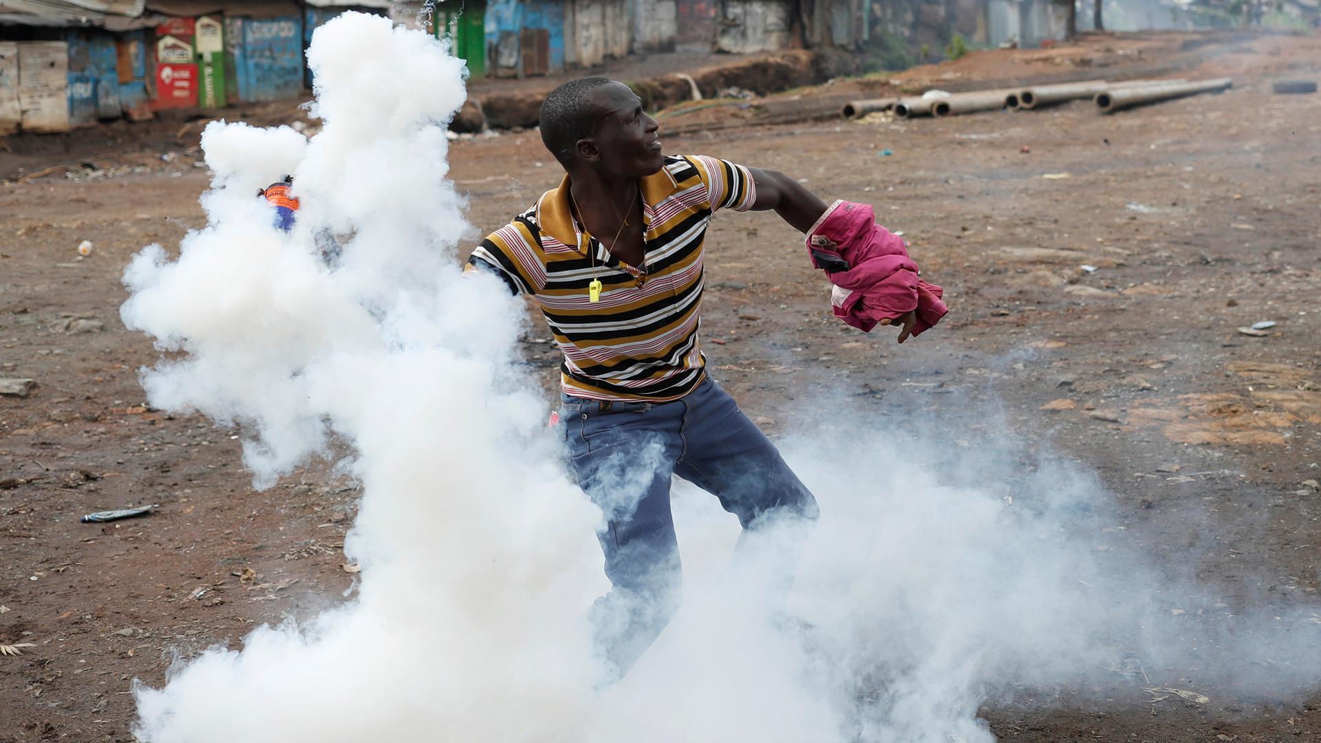 An opposition supporter returns a teargas canister fired by police during clashes in Kibera slum in Nairobi, Kenya, Oct. 26, 2017.