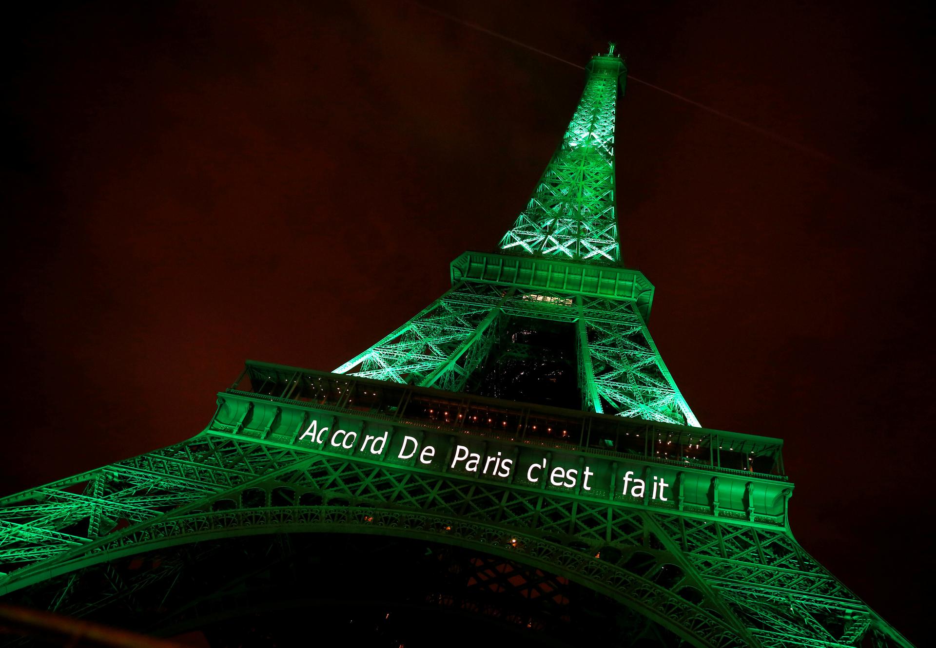 The Eiffel tower is illuminated in green with the words "Paris Agreement is Done