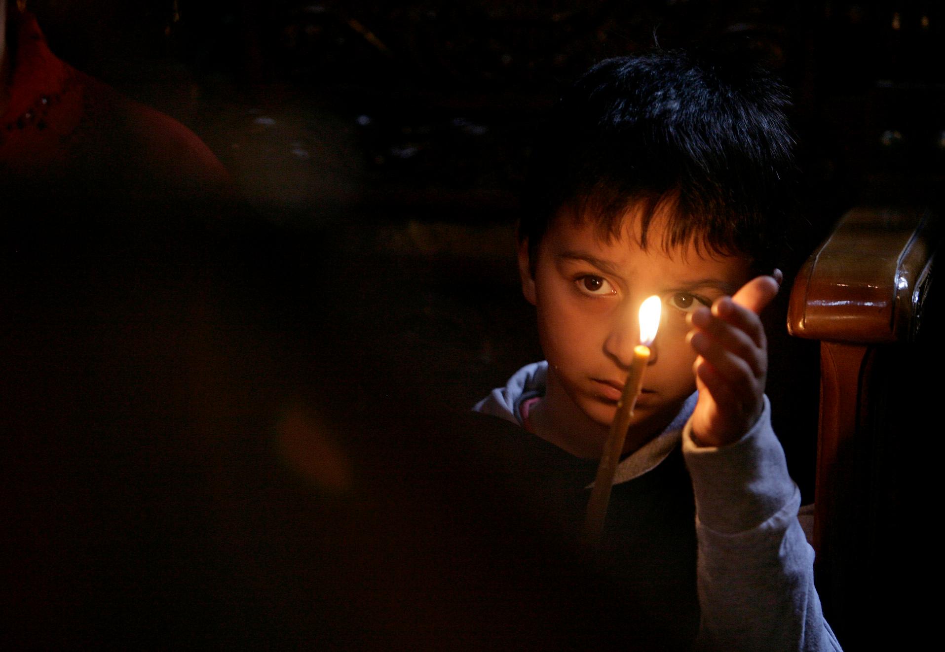 A child from the Roma community holds a candle at a church in Bucharest