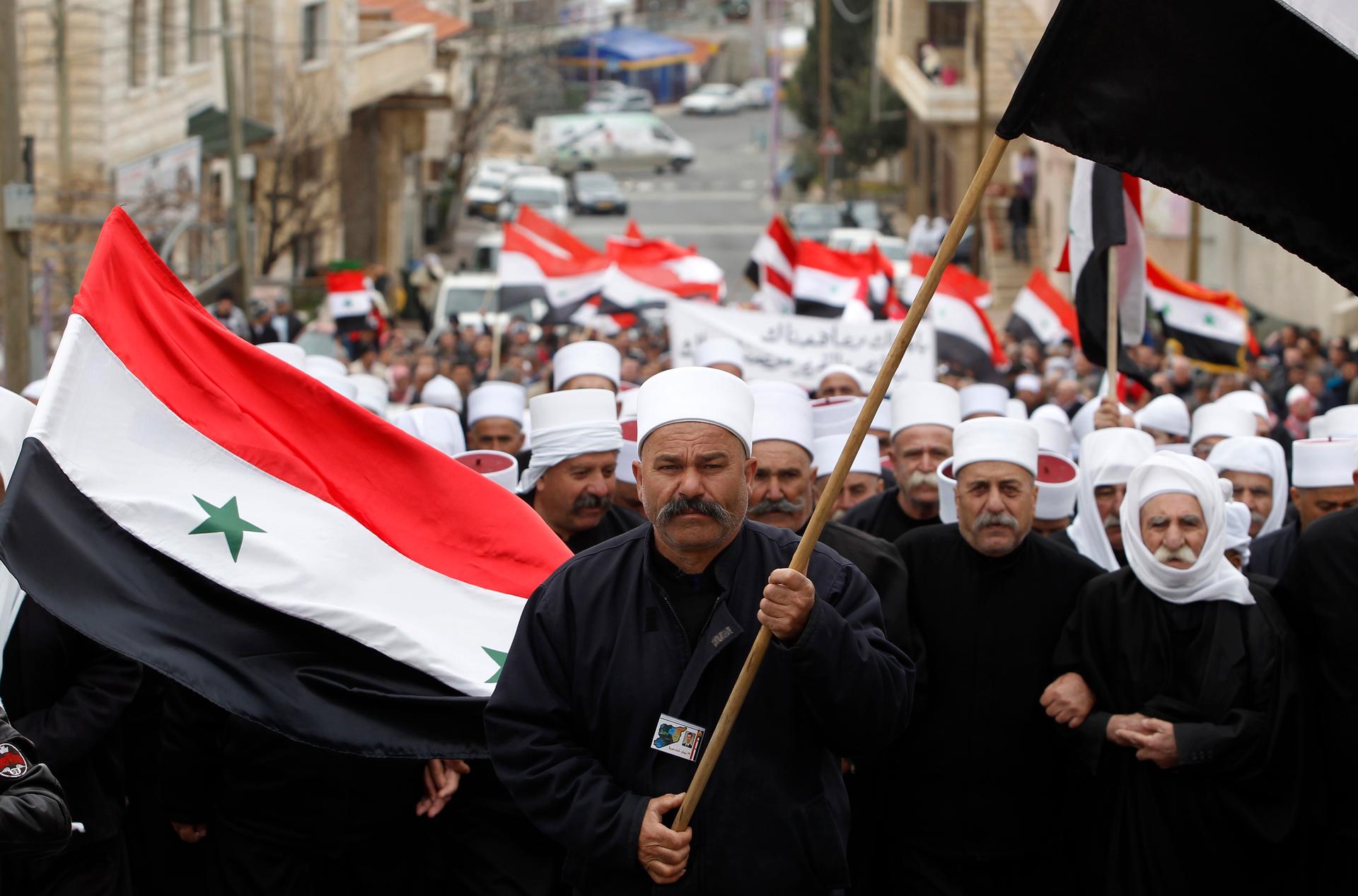 Members of the Druze community hold Syrian flags during a rally in the Druze village of Majdal Shams in the Golan Heights, Feb. 14, 2013.