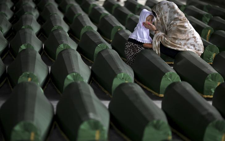 A Bosnian Muslim woman and child cry near the coffin of their relative, which is one of the 175 coffins of newly identified victims from the 1995 Srebrenica massacre, in the Potocari Memorial Center, near Srebrenica, July 10, 2014. 