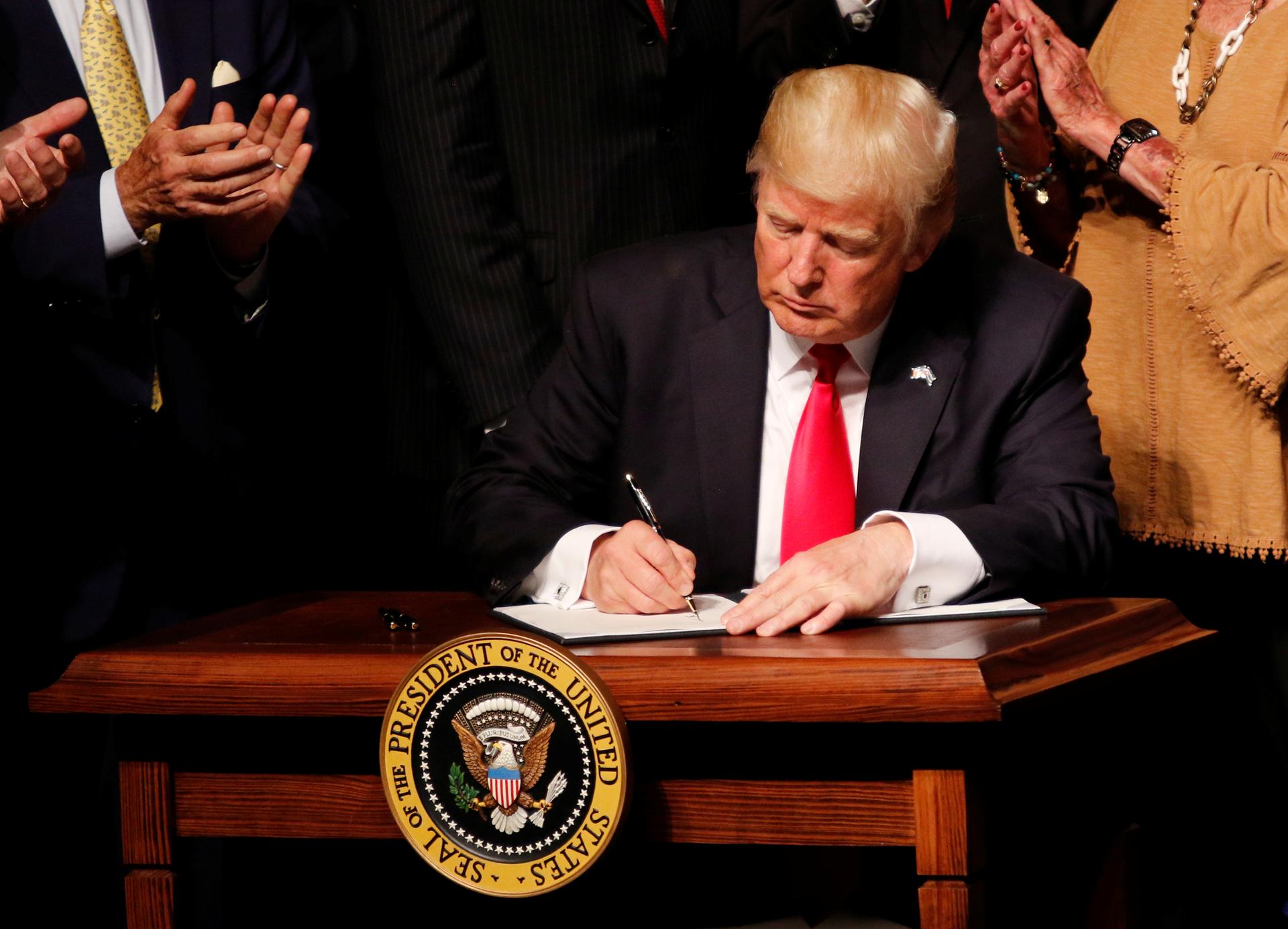 US President Donald Trump signs a document after announcing his Cuba policy