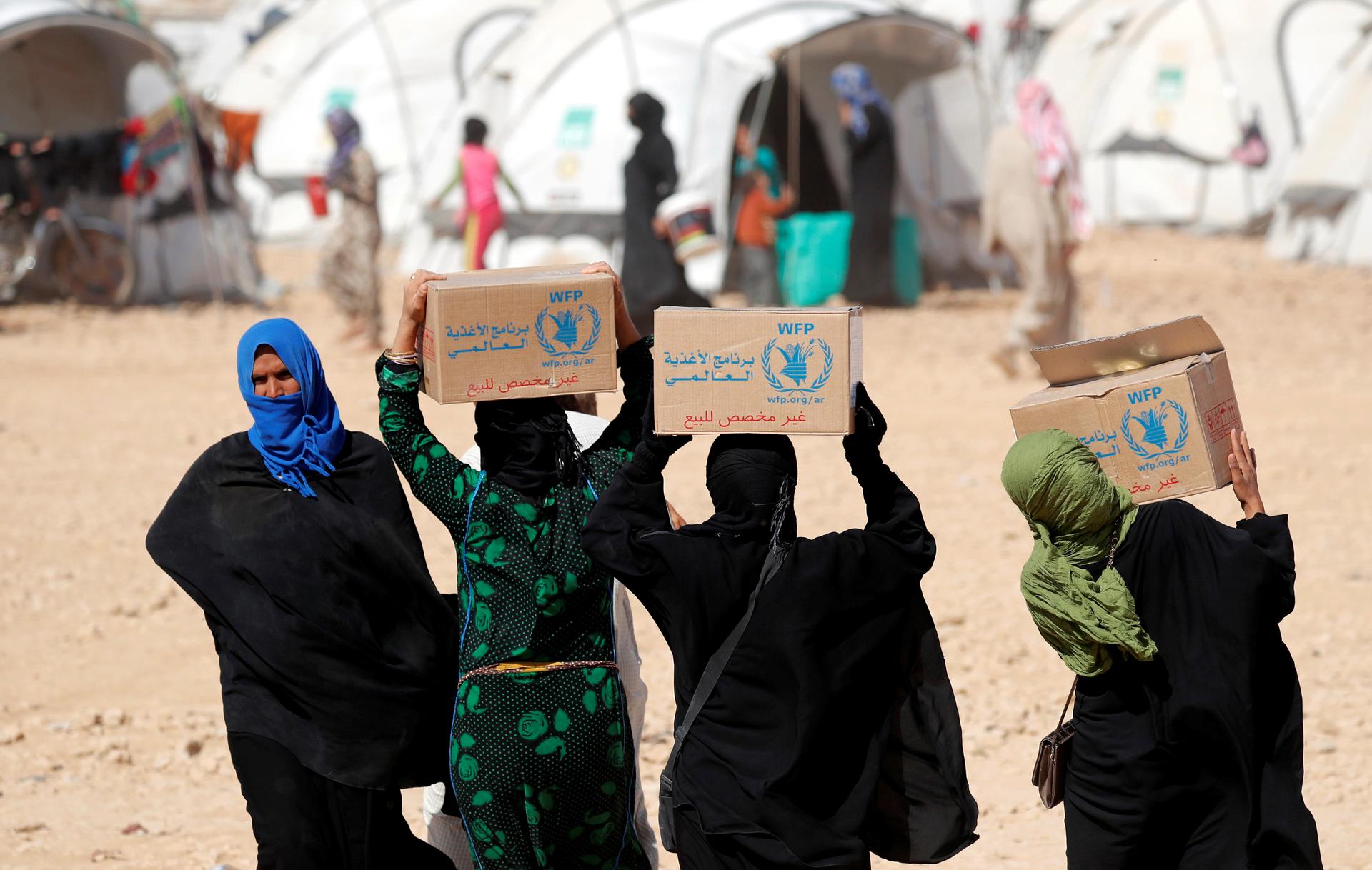 People displaced by the Syrian civil war carry boxes of food aid distributed by the UN's World Food Program at a refugee camp in Ain Issa, Syria, Oct. 10, 2017.