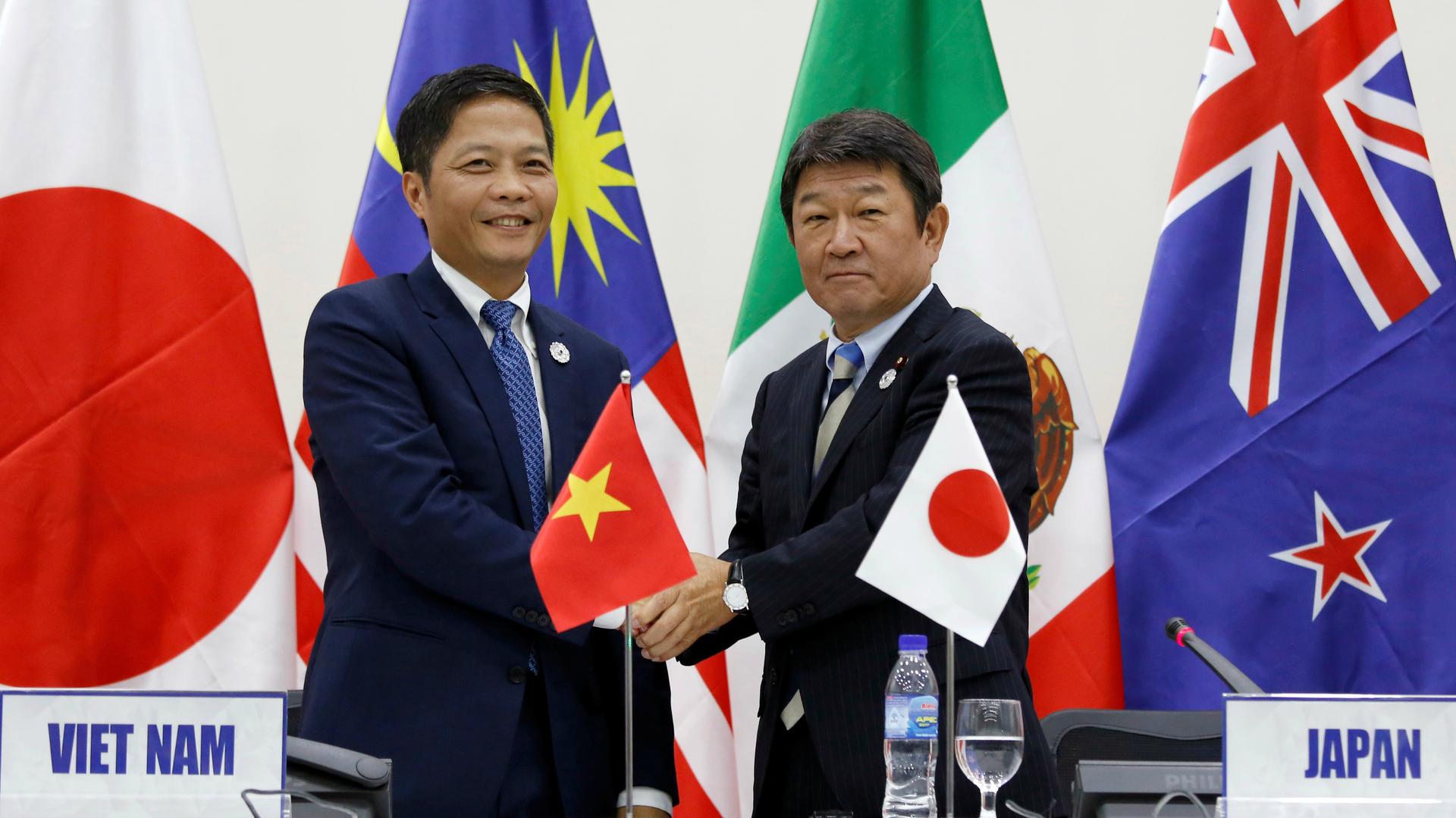 Japan's Minister of Economic Revitalization Toshimitsu Motegi, right, and Vietnam's Industry and Trade Minister Tran Tuan Anh shake hands after they attended a news conference on the Trans Pacific Partnership (TPP) Ministerial Meeting during APEC 2017 in