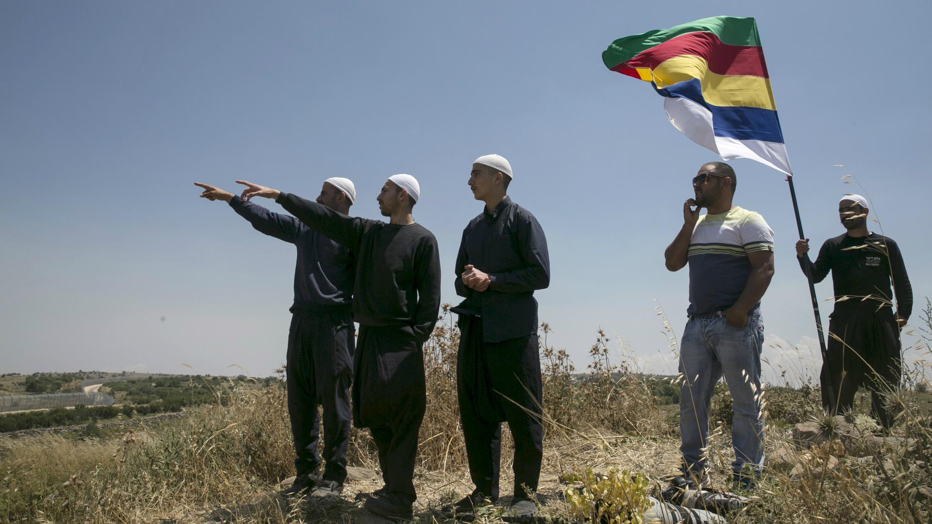 Members of the Druze community watch the fighting in Syria's civil war, next to the border fence between Syria and the Israeli-occupied Golan Heights, near the Druze village of Majdal Shams, June 16, 2015.