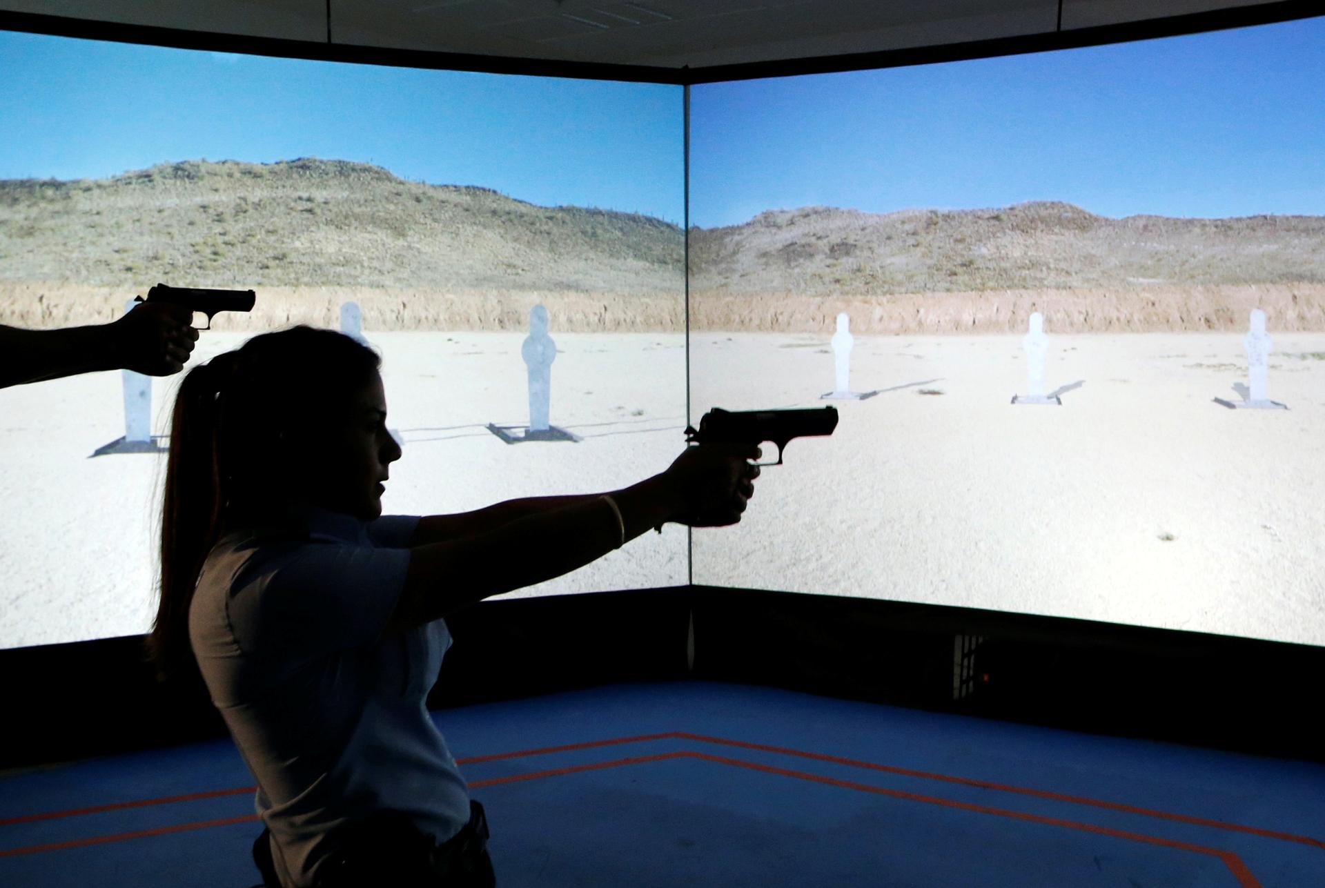 An Arab Israeli police recruit takes aim with her gun towards a screen displaying targets