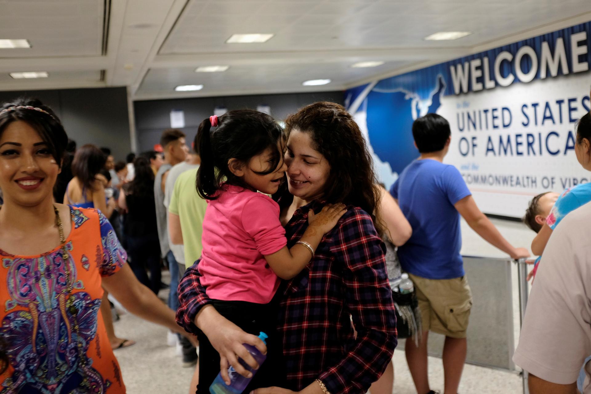 Zarfishan Zahid (L) smiles as Sana Tahir (R) holds Malaika Noman, 3, as the child arrives in the United States after a federal judge ruled in July that President Trump's temporary ban on travelers from six Muslim-majority countries cannot stop grandparent
