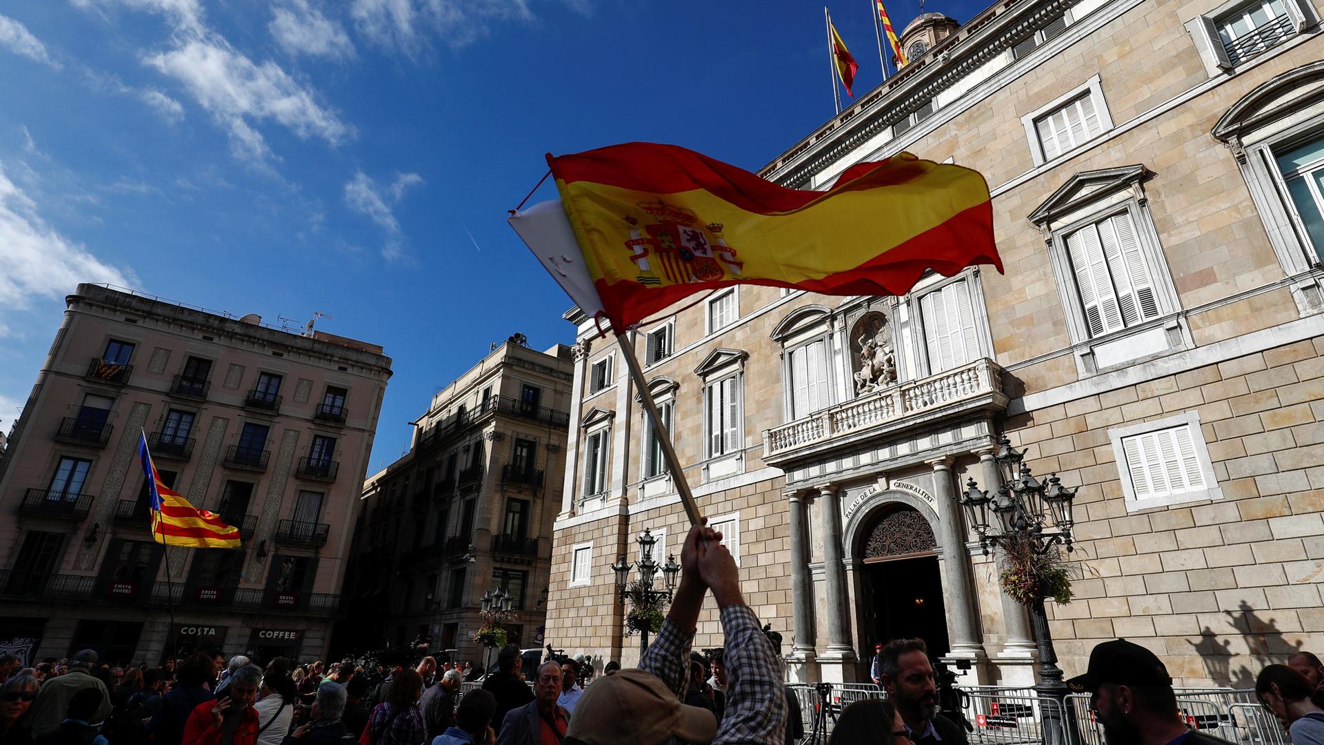 Spanish and Catalan flags are waved in front of the Generalitat Palace, the Catalan regional government headquarters in Barcelona, Oct. 30, 2017.