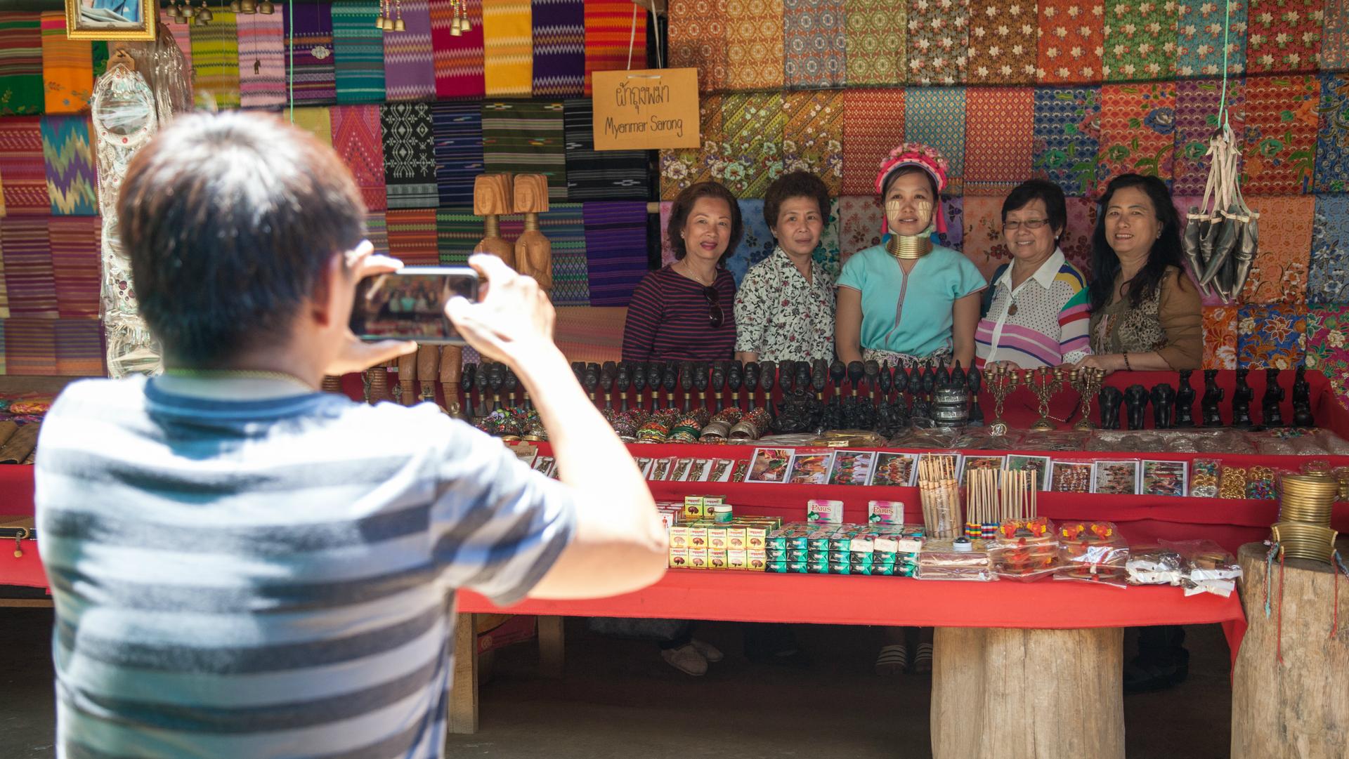 Thai tourists from Bangkok take a photo with one of the women at Huai Sua Tao. 