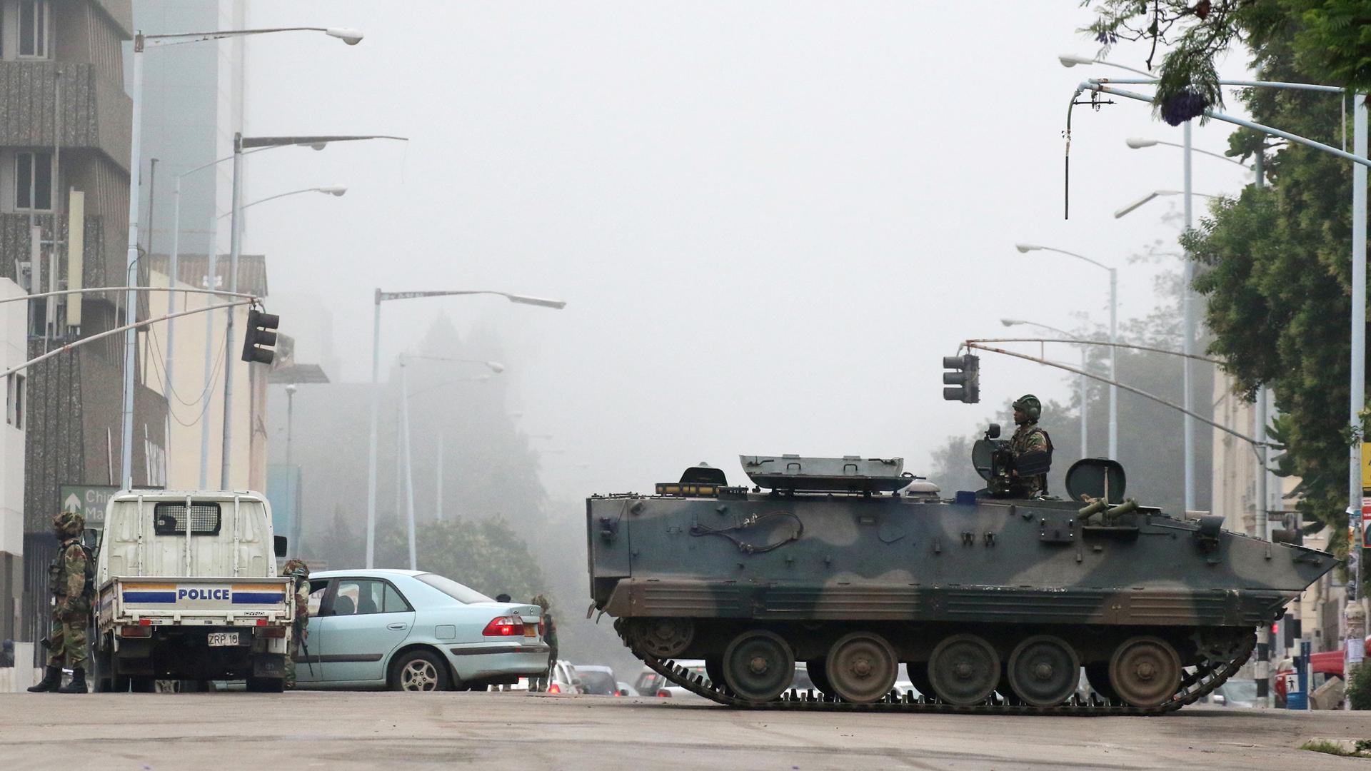 A tank with a soldier standing up on top is parked in the middle of the street in Harare, Zimbabwe,