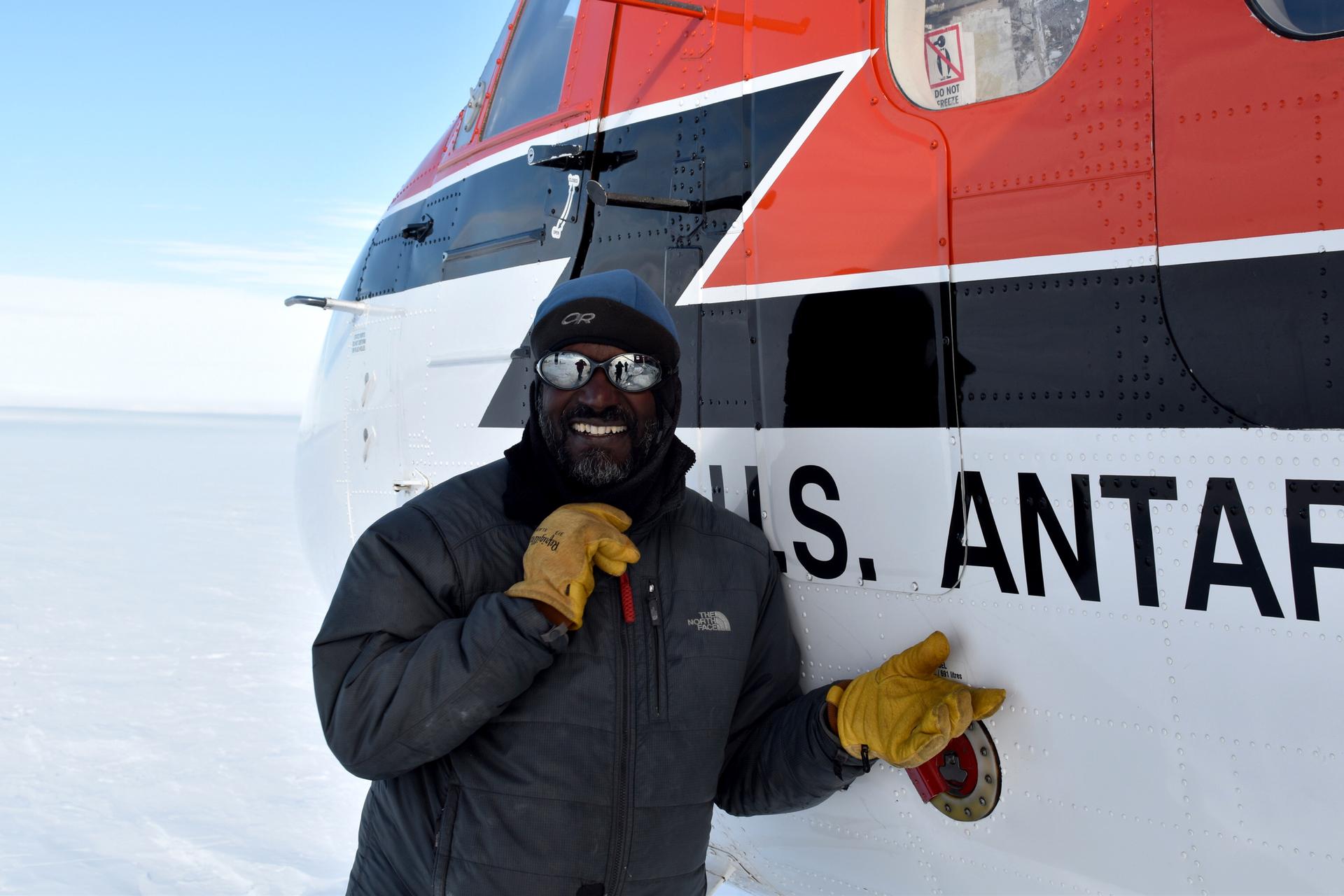 A man smiles in a posed photo in front of a Twin Otter airplane.