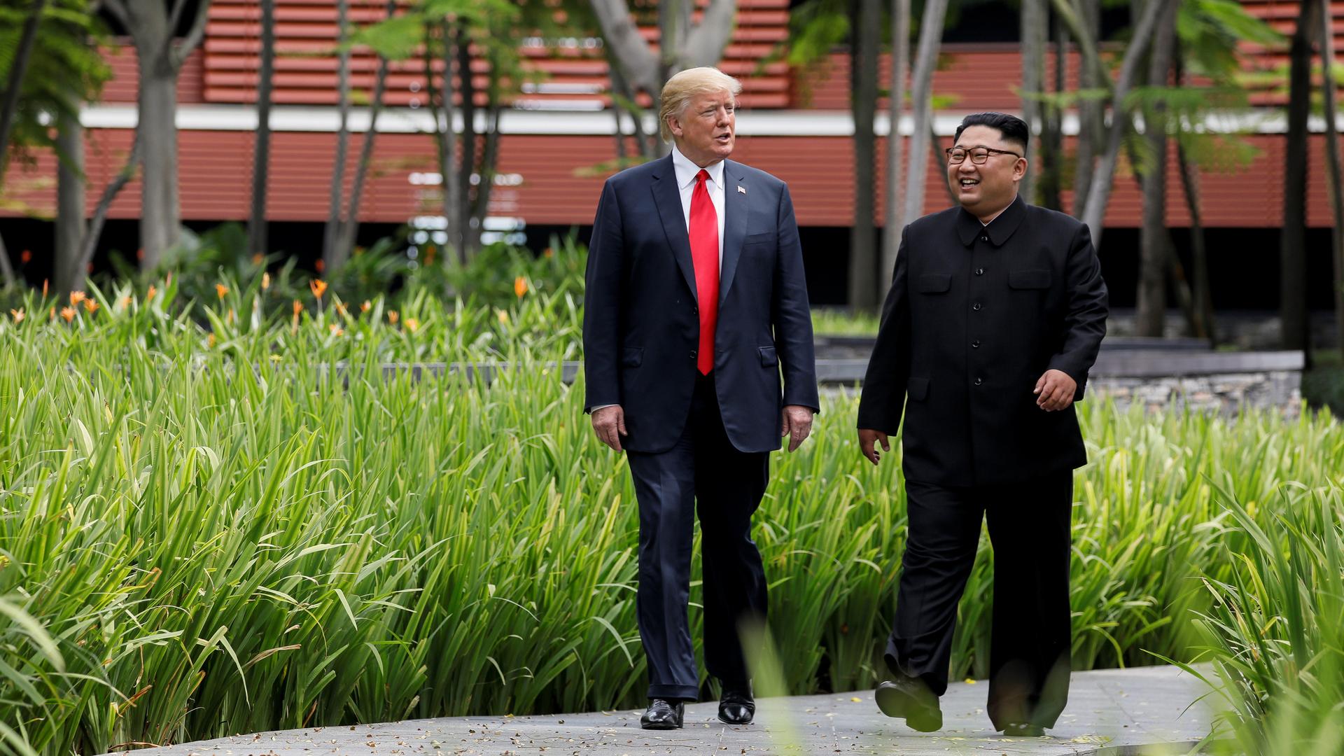 US President Donald Trump and North Korea's leader Kim Jong Un walk together before their working lunch during their summit at the Capella Hotel on the resort island of Sentosa, Singapore.