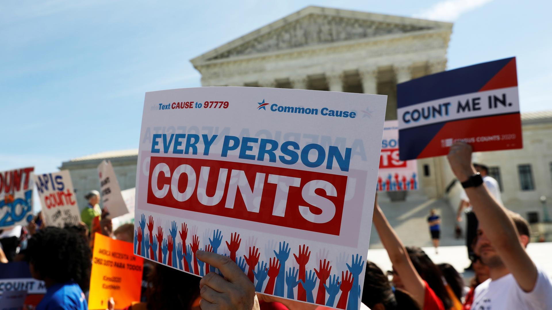 Protesters stand outside court with sign that reads "Every person counts"