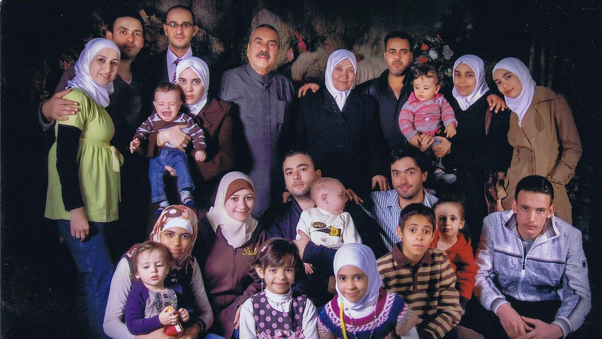 A family portrait with several younger children in the front row and adults in the back row.