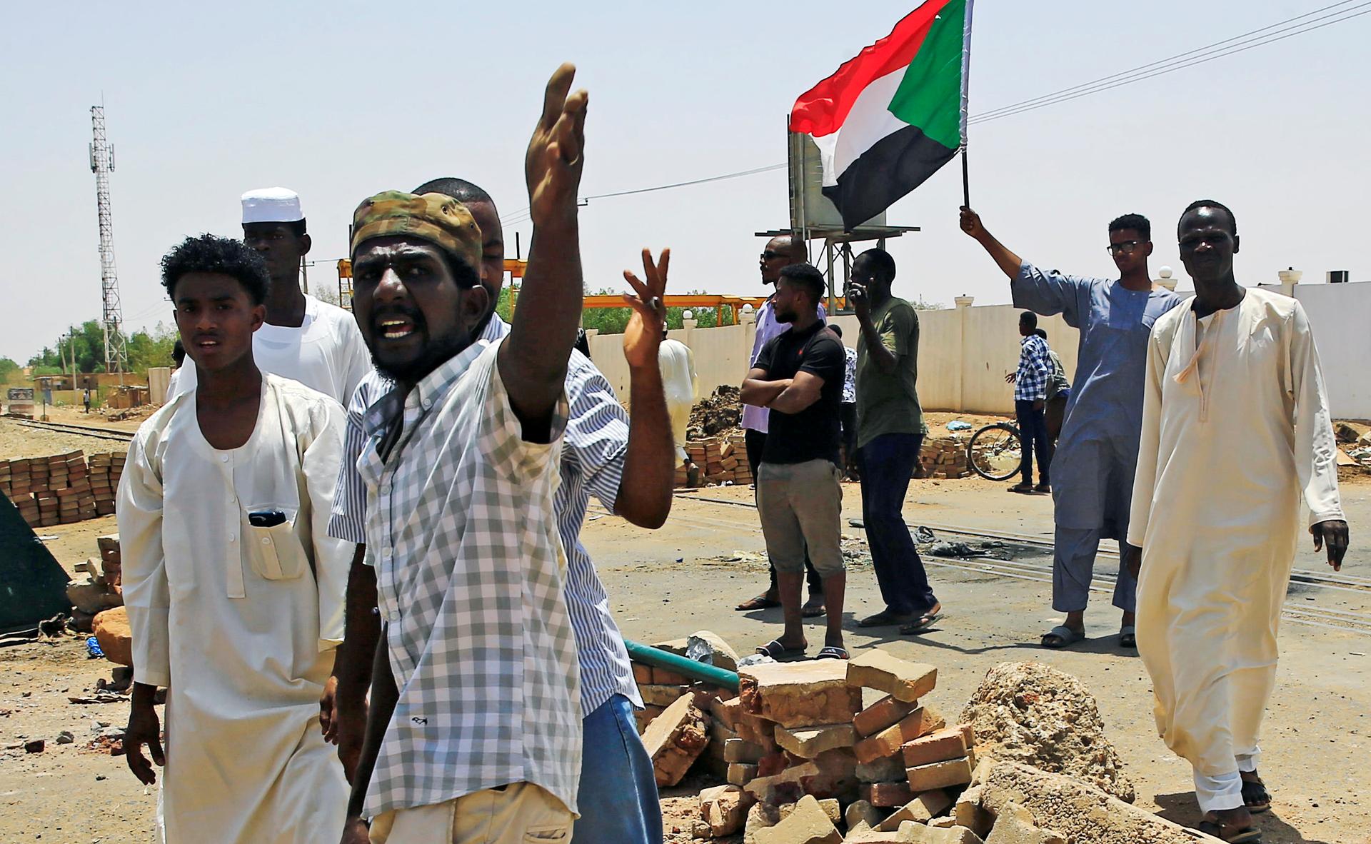 Men set up barricade and wave flag of Sudan