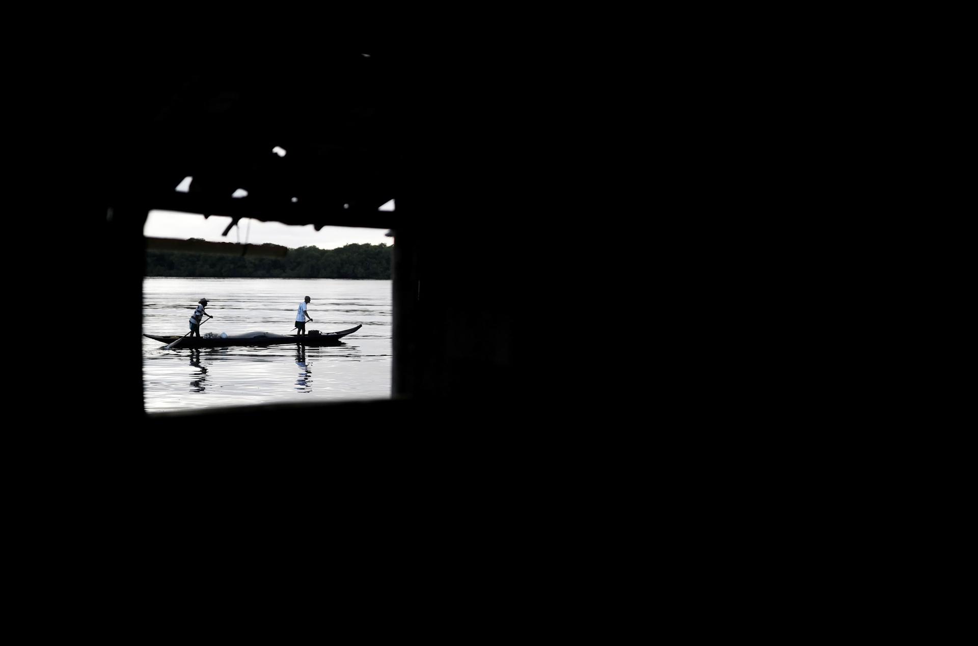 A dark photograph with a bright window showing people on a boat.