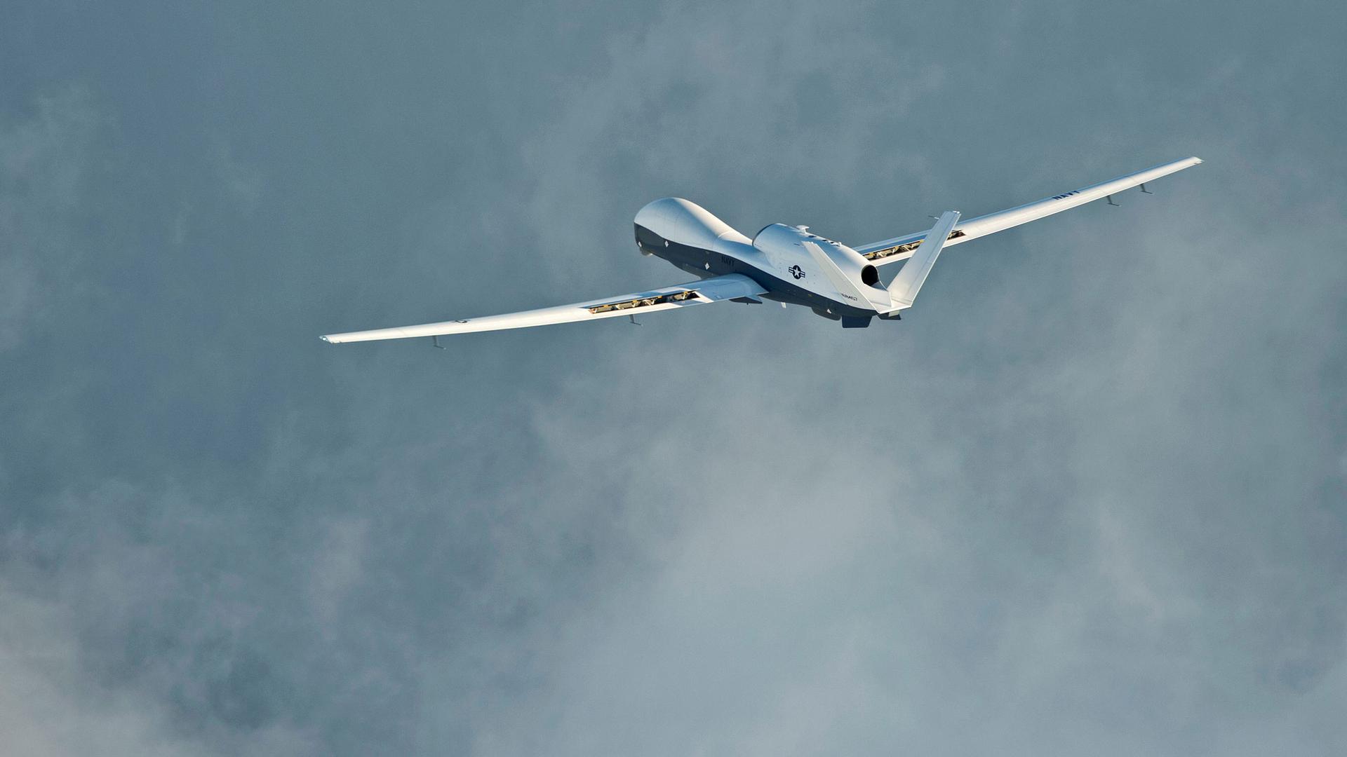 A large military drone is shown with a white top and dark underside.